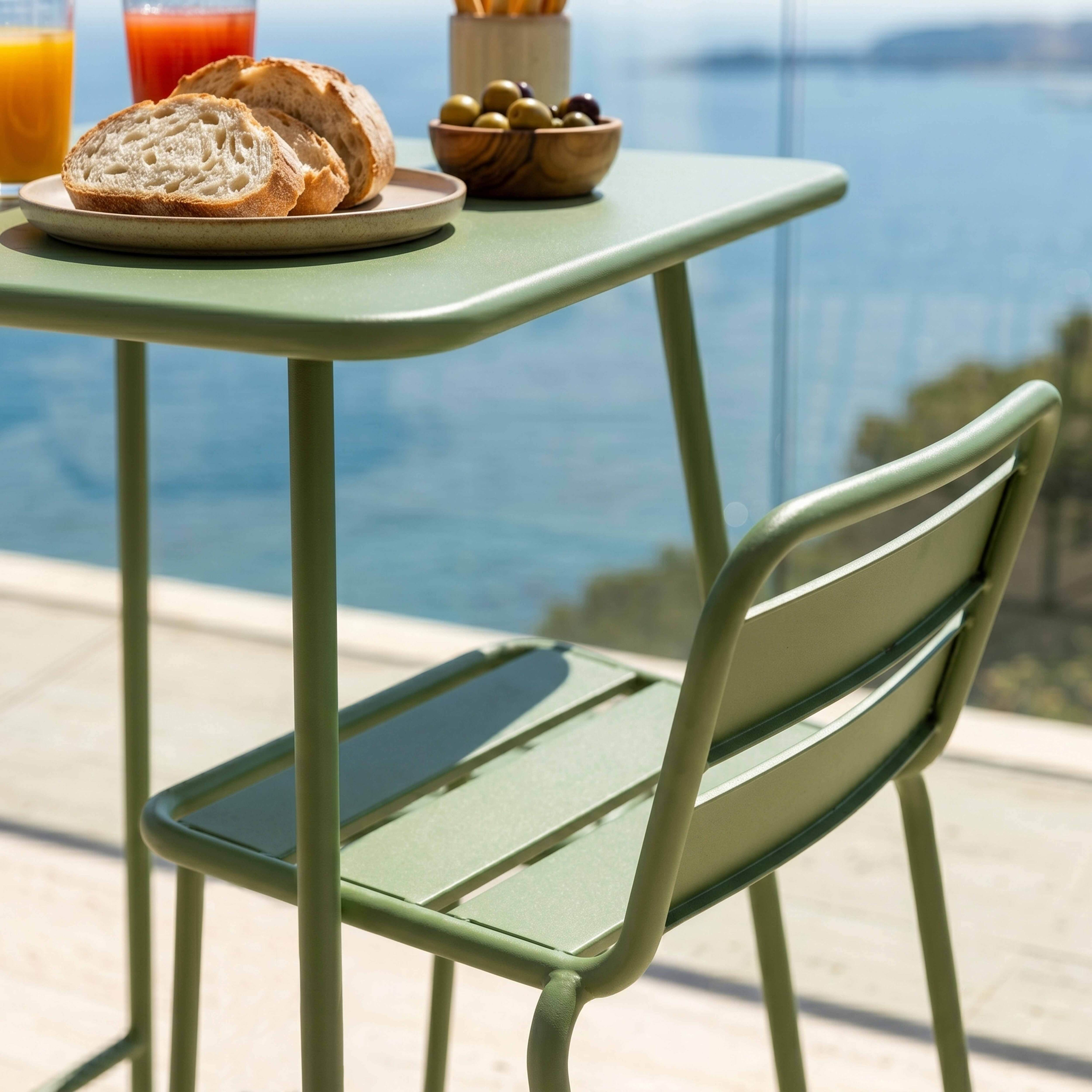 Grüner Tisch mit Brot, Oliven, Saft und Meerblick.