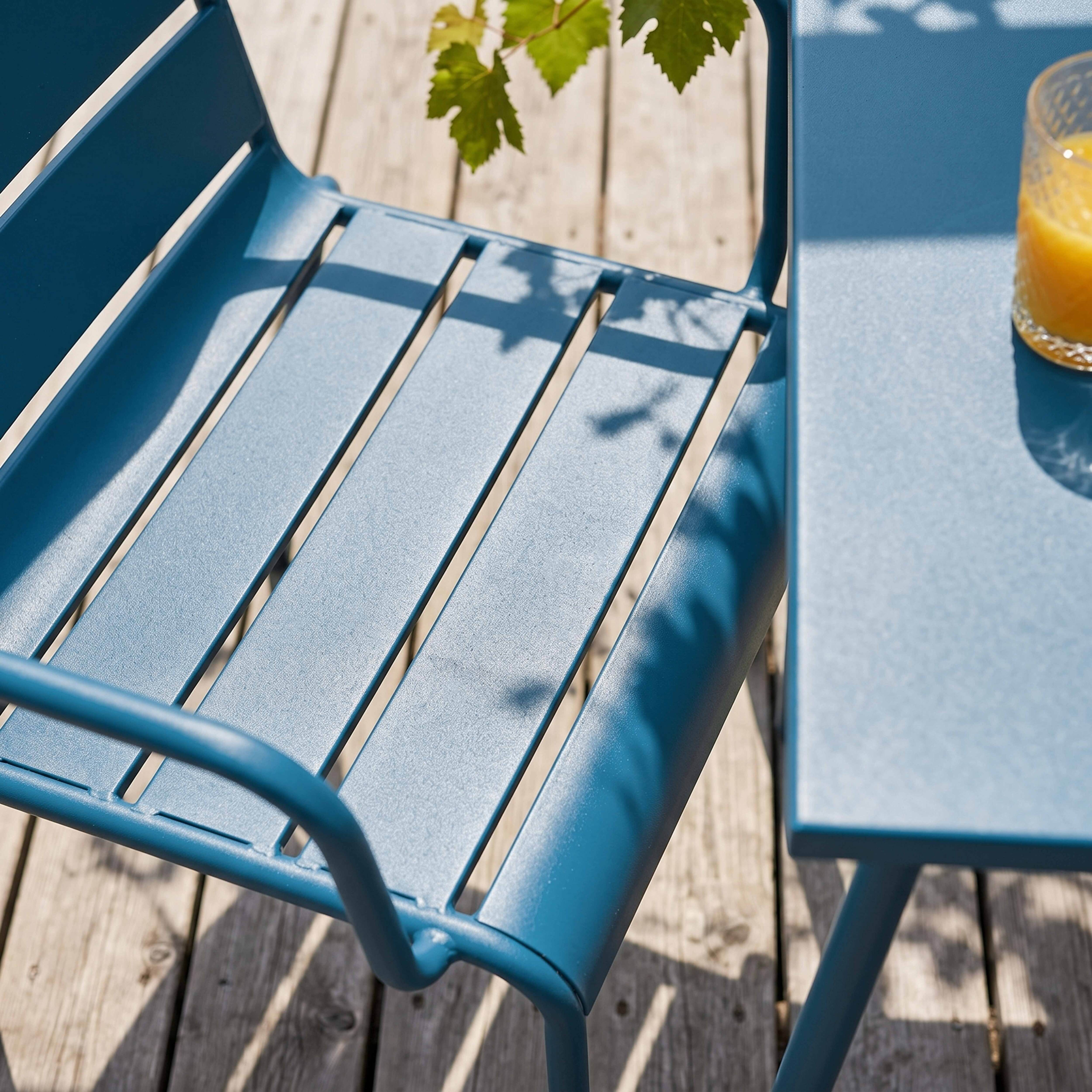 Blaue Gartenmöbel auf Holzterrasse mit einem Glas Orangensaft.