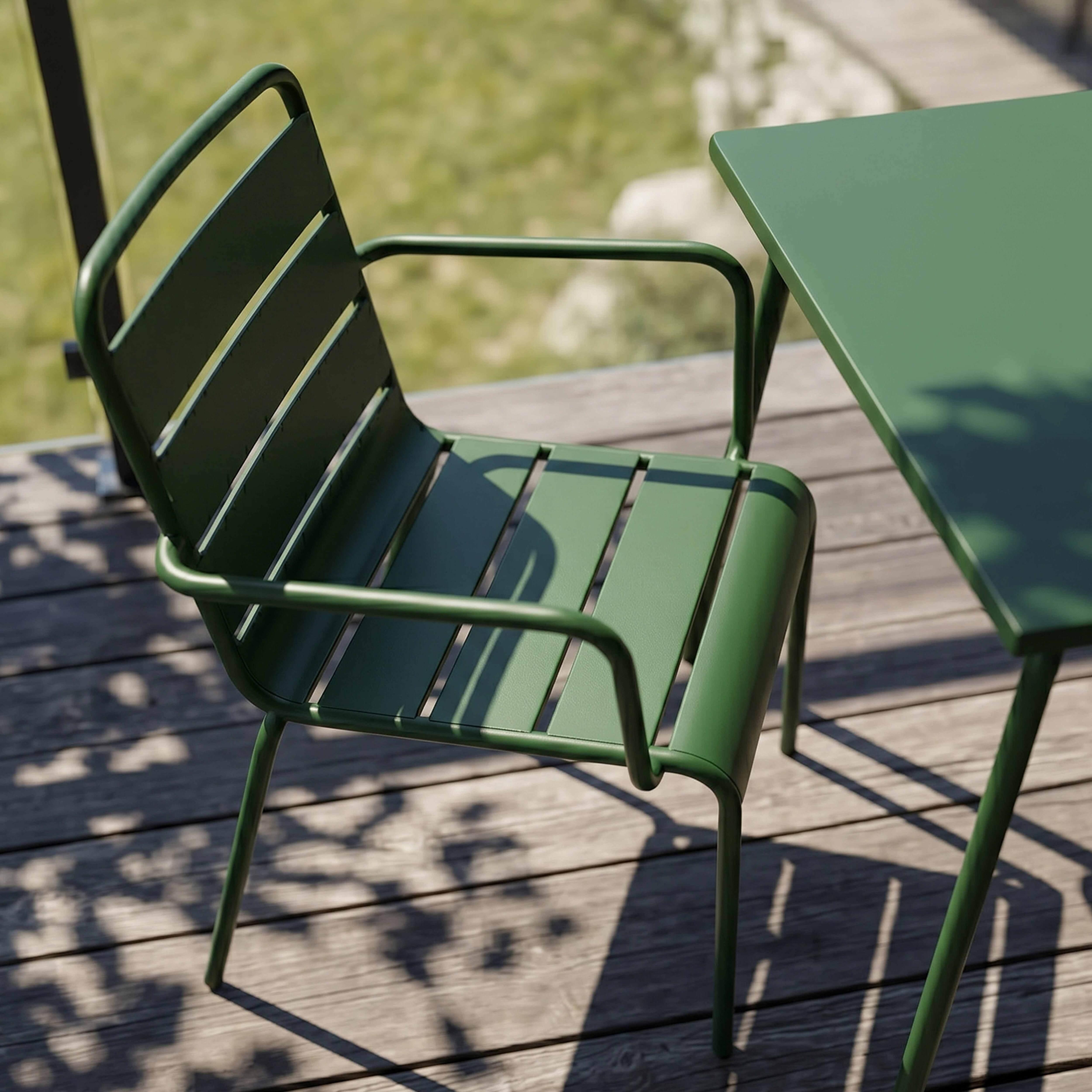 Ein grüner Metallstuhl und ein Tisch stehen auf einer Holzterrasse im Freien.