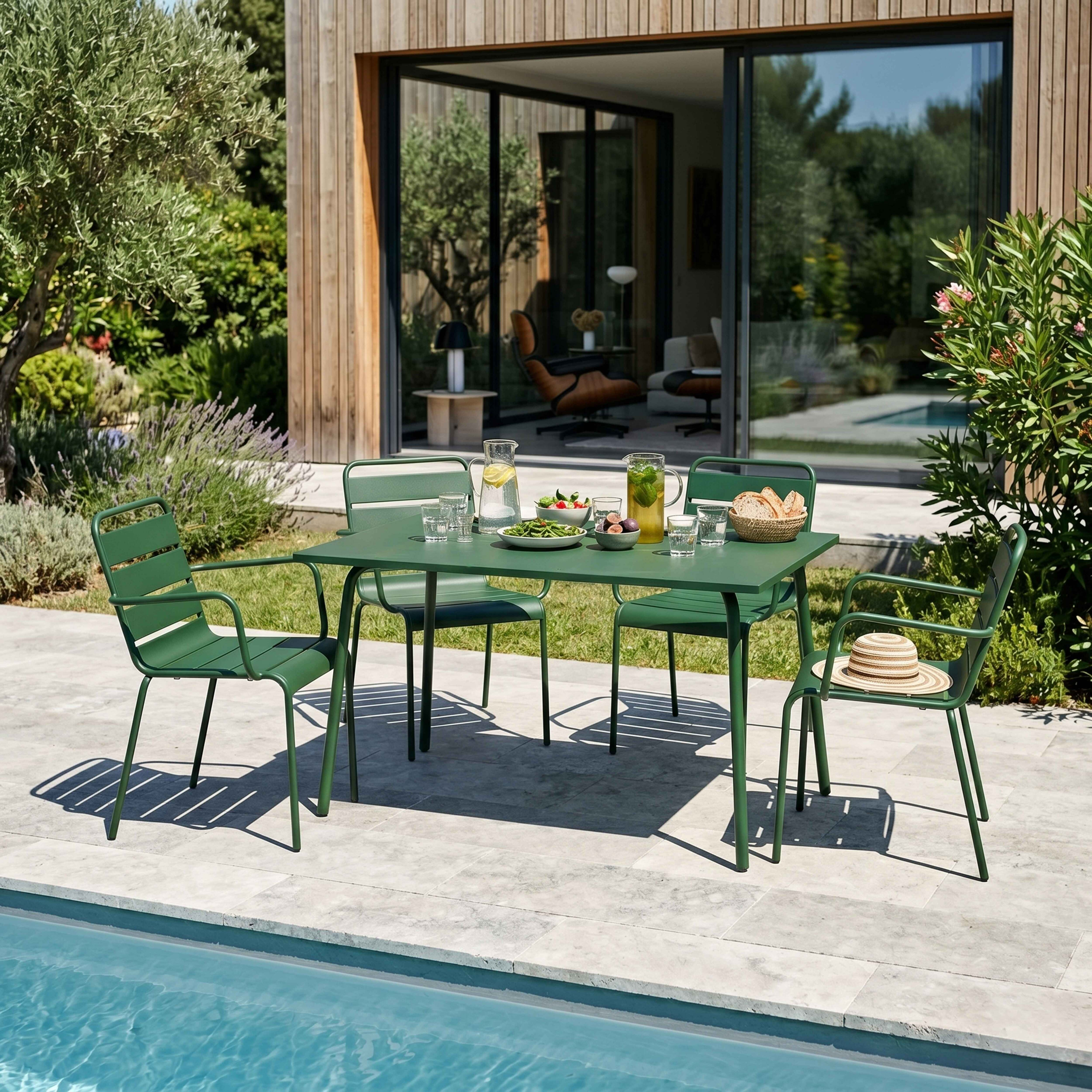 Grüne Gartenmöbel am Pool mit Serviertisch, Gläsern, Krügen und Obst.