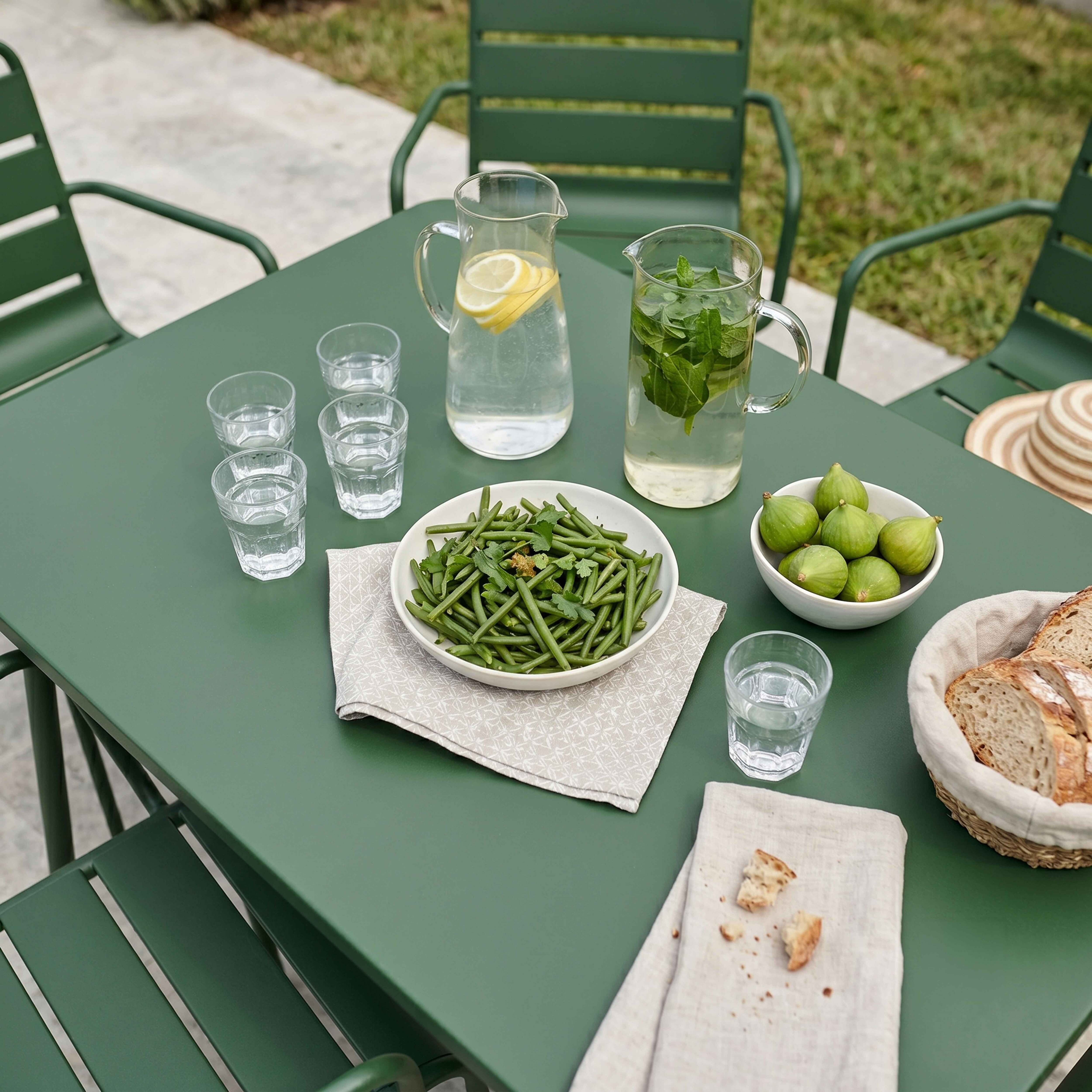 Grüner Tisch mit Essen: grüne Bohnen, Feigen, Brot und Getränke mit Zitrone und Minze.