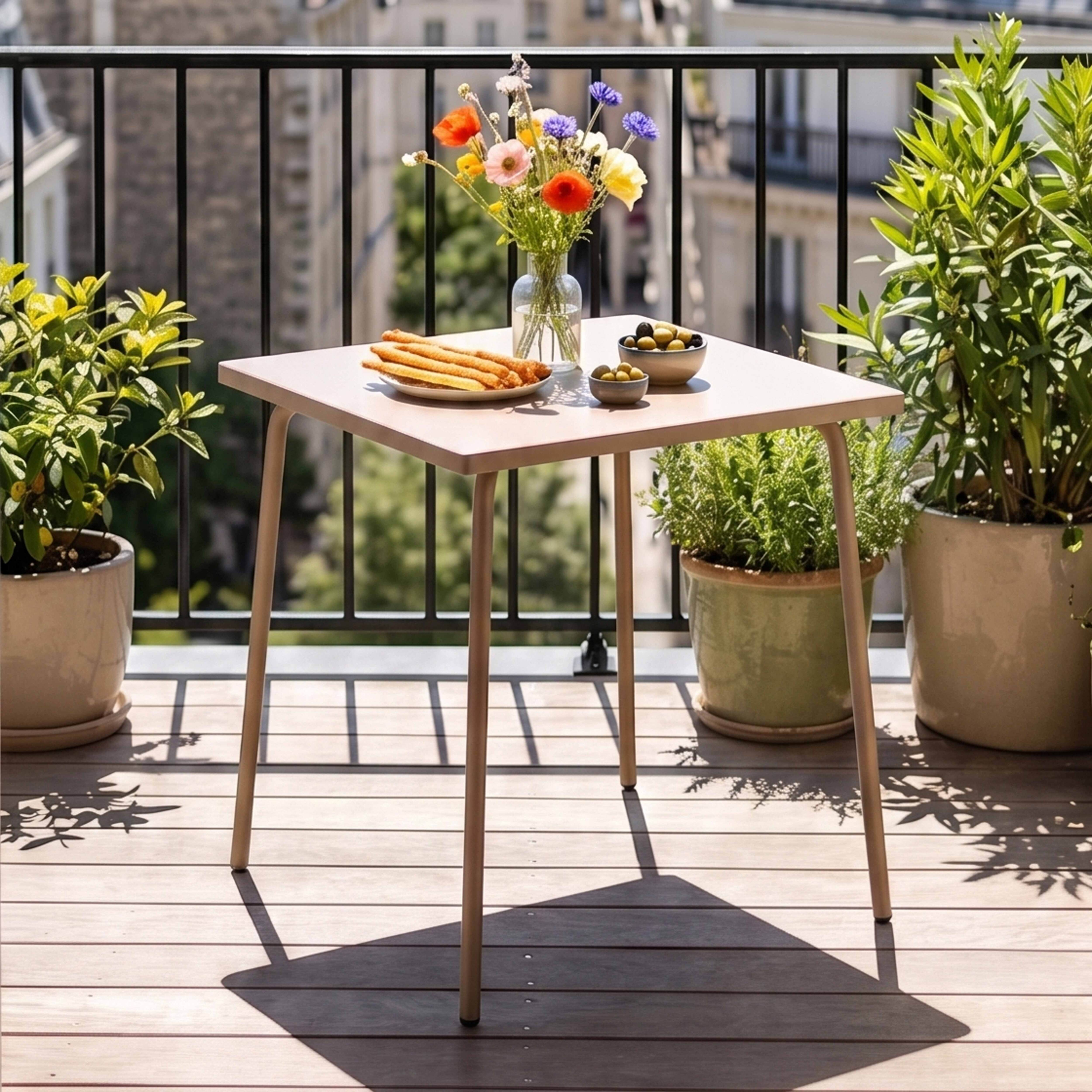 Ein Tisch auf einem Balkon mit Blumen, Brotstangen und Oliven. Pflanzen umgeben den Tisch.