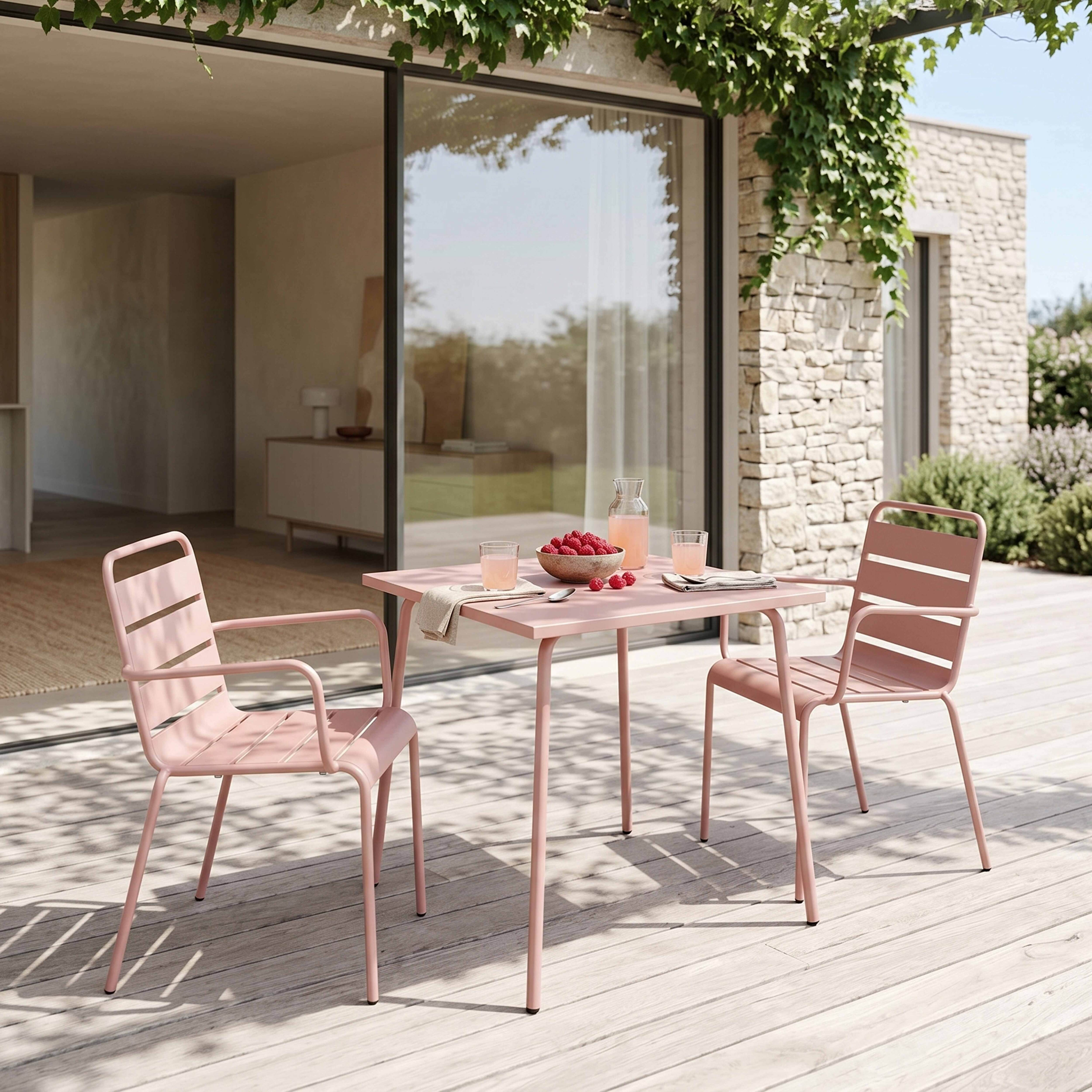 Ein rosafarbener Gartentisch mit zwei Stühlen und Himbeeren.
