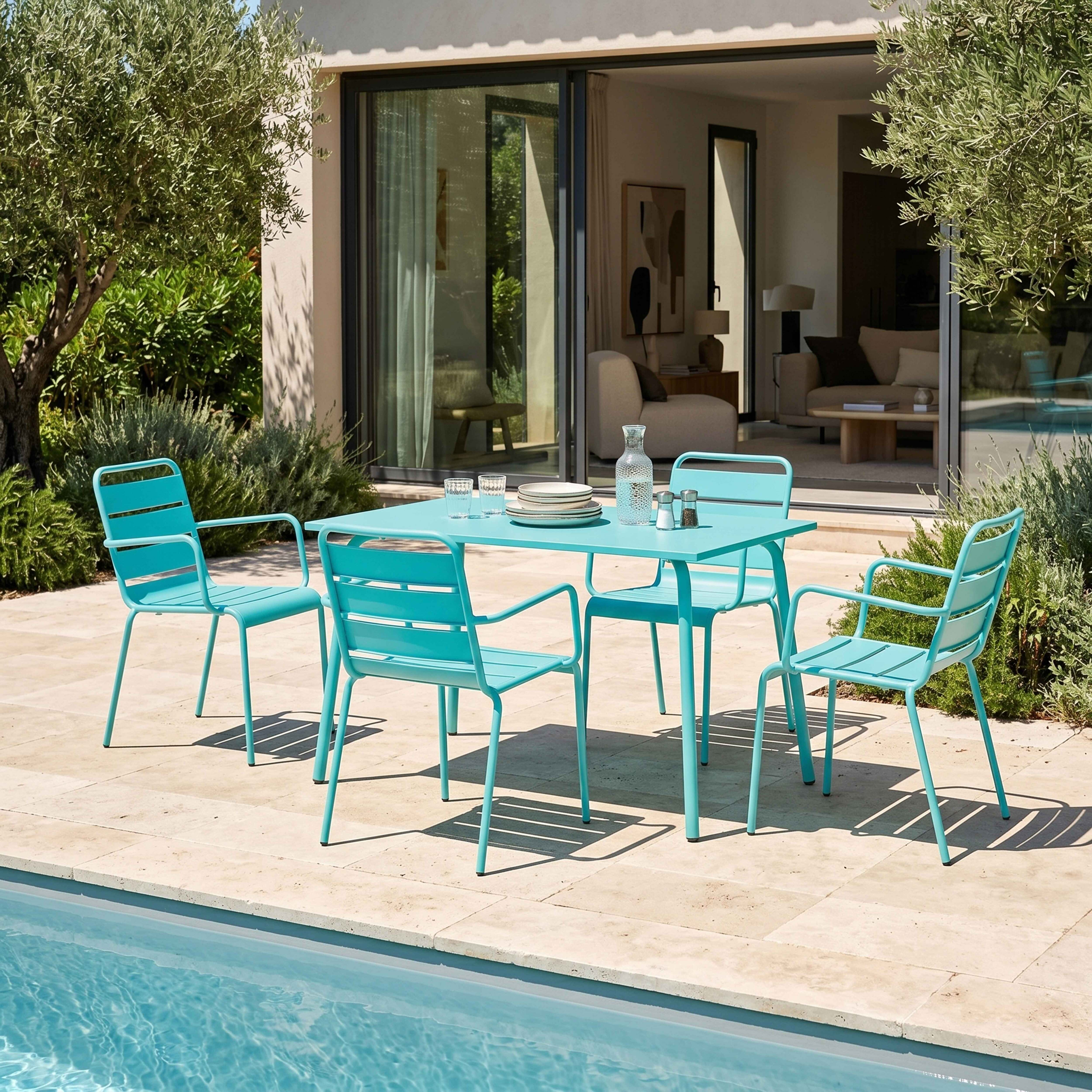 Türkisfarbene Gartenmöbel am Pool mit Olivenbaum und Haus im Hintergrund.