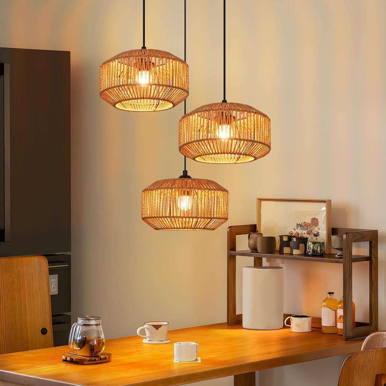 Drei geflochtene Hängelampen hängen über einem Holztisch mit Teekanne, Tassen und einem Regal mit Deko.