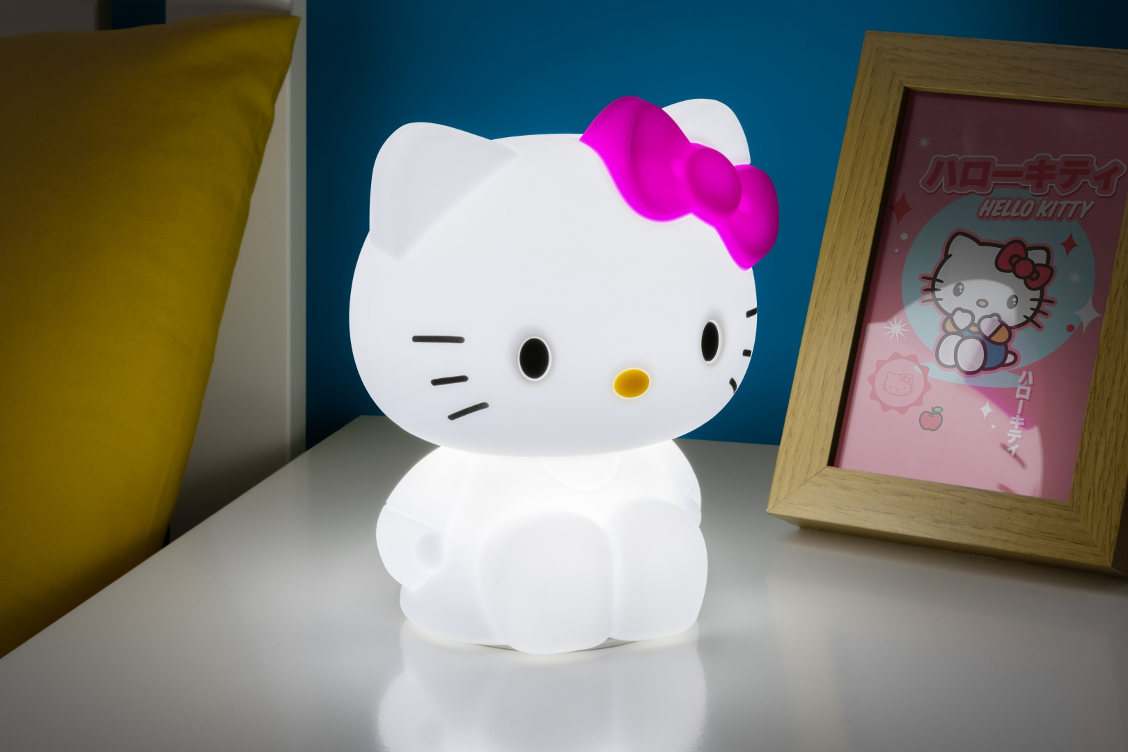 Eine leuchtende Hello Kitty Lampe neben einem gerahmten Bild.
