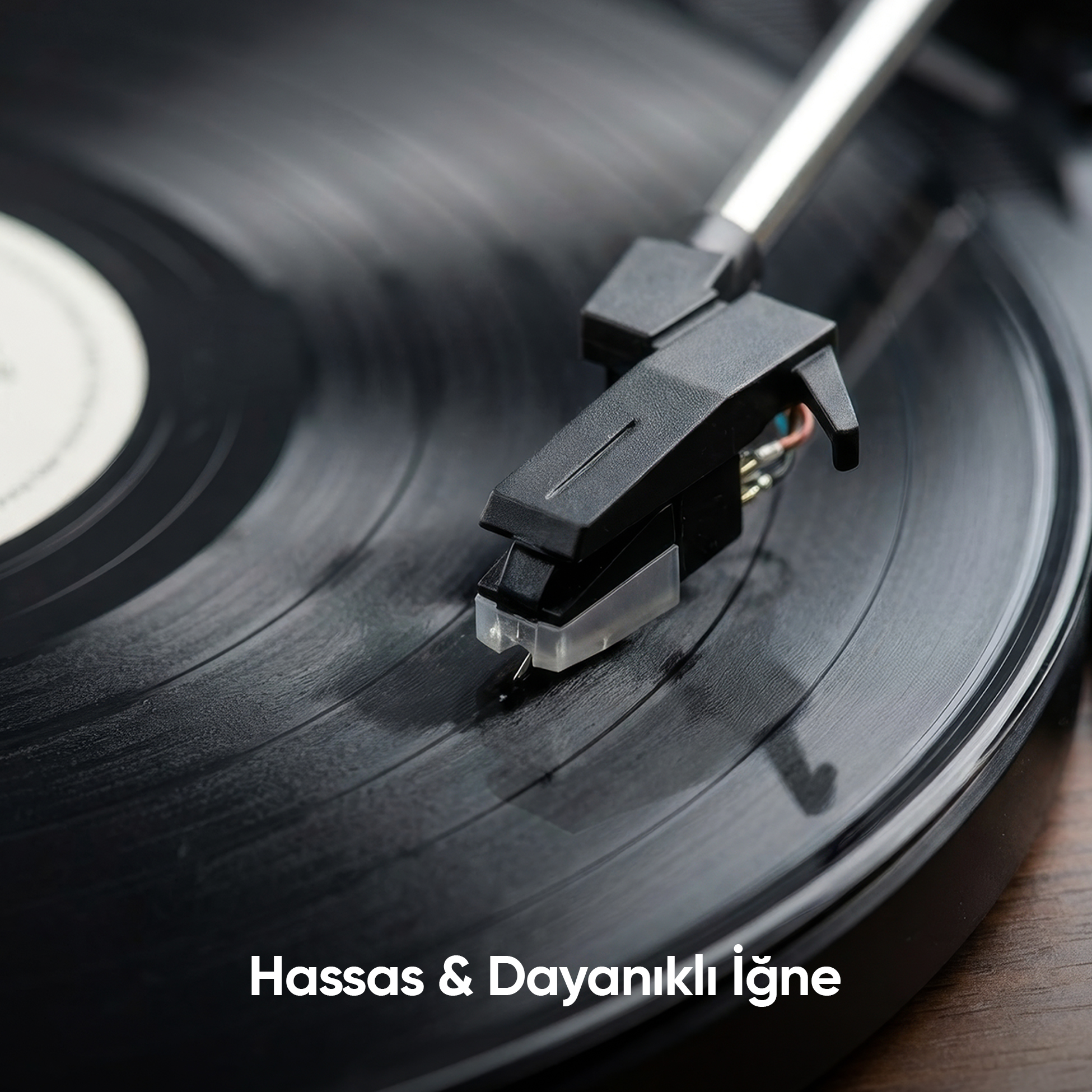 Bir pikap iğnesi siyah bir vinil plağın üzerinde duruyor.