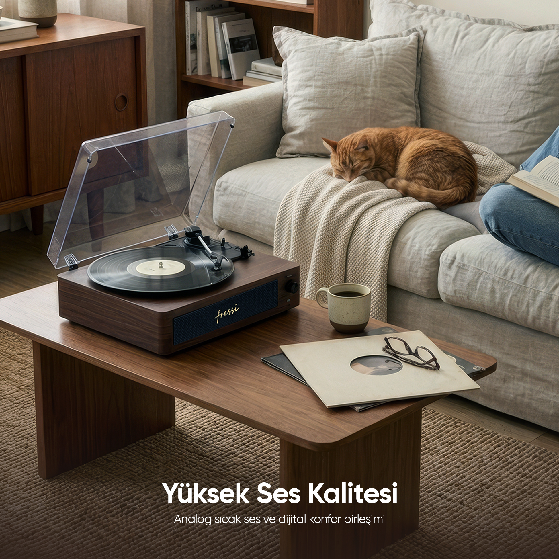 Masanın üzerinde pikap, yanında kupa ve uyuyan kedi.