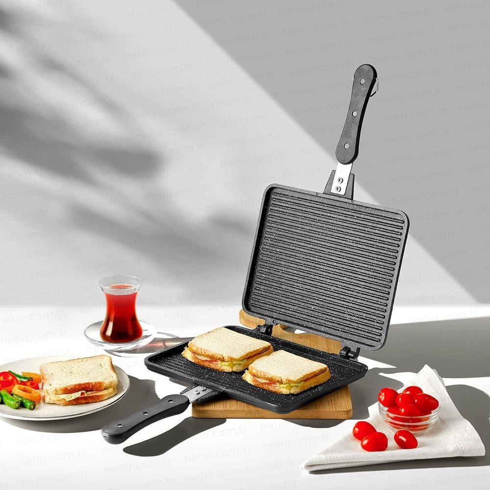 İki sandviç, domates, salatalık ve bir bardak çay ile sandviç grill makinesi.