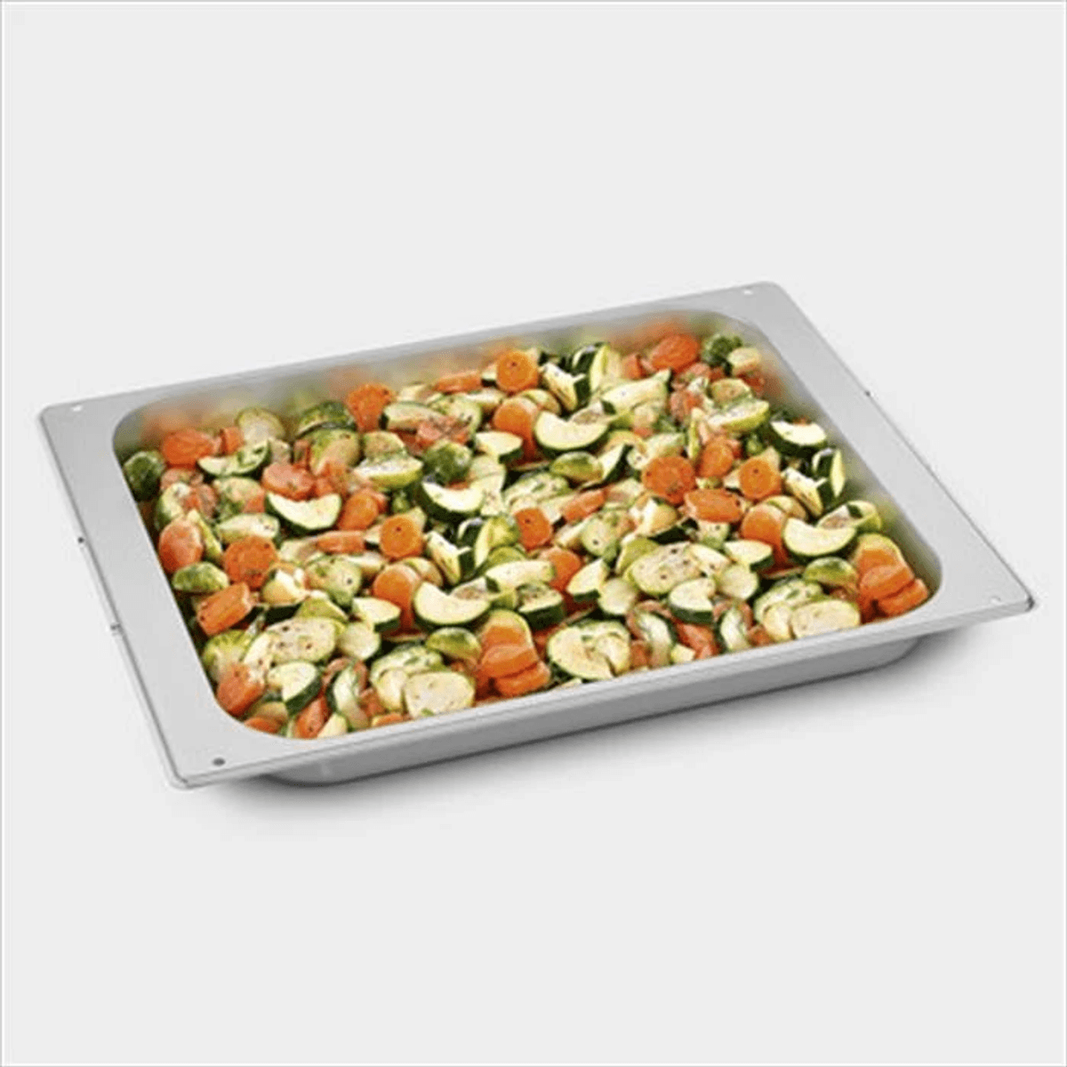 Una bandeja metálica llena de zanahorias y calabacines picados.
