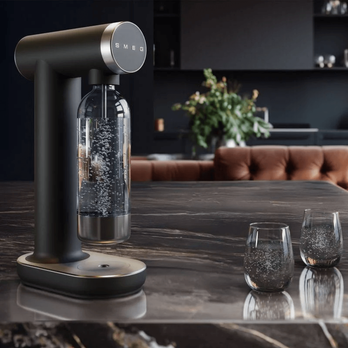 Un carbonatador de agua negro con una botella de vidrio, y dos vasos al lado.