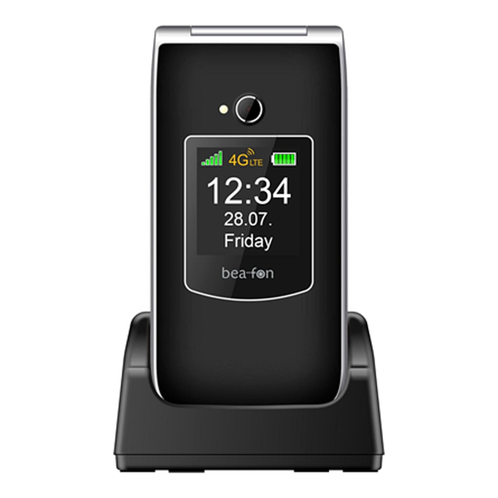 Un telefono flip nero su base di ricarica. Lo schermo mostra 12:34, venerdì 28.07.