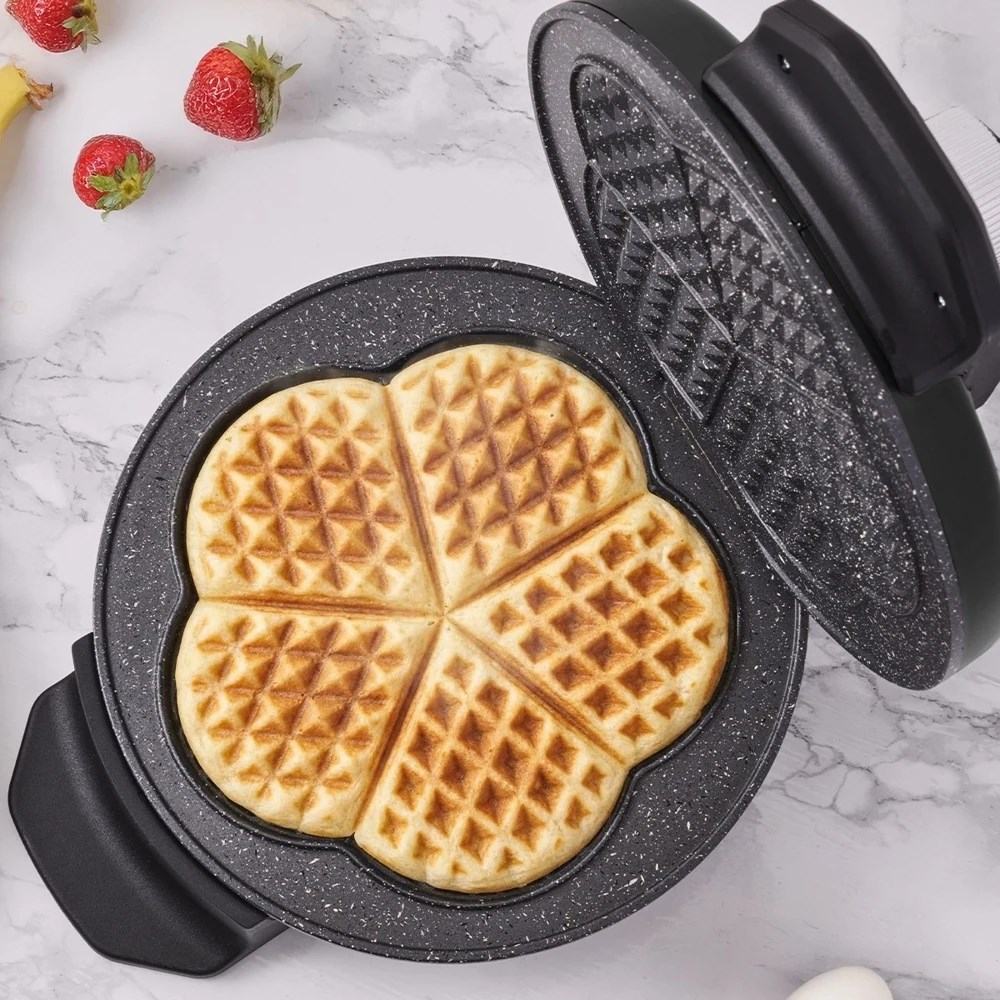 Mermer üzerinde dört waffle ve çilek bulunan kalp şeklinde waffle makinesi.