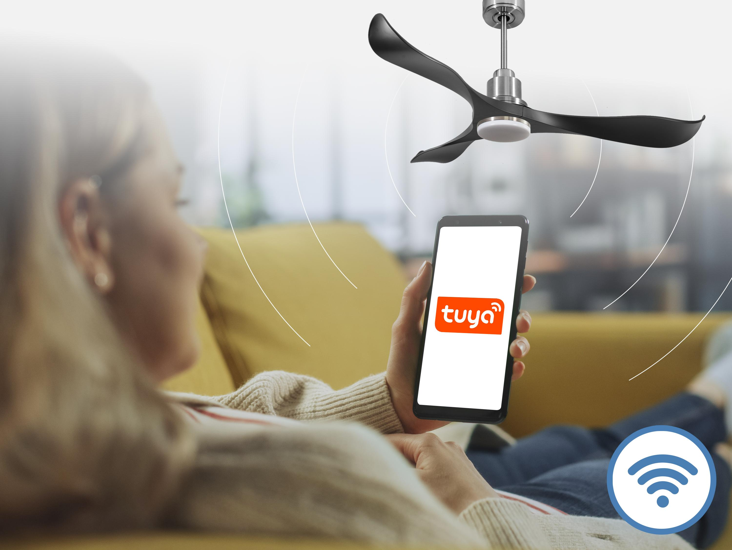 Una mujer en un sofá usa un smartphone con la app Tuya para controlar un ventilador de techo.