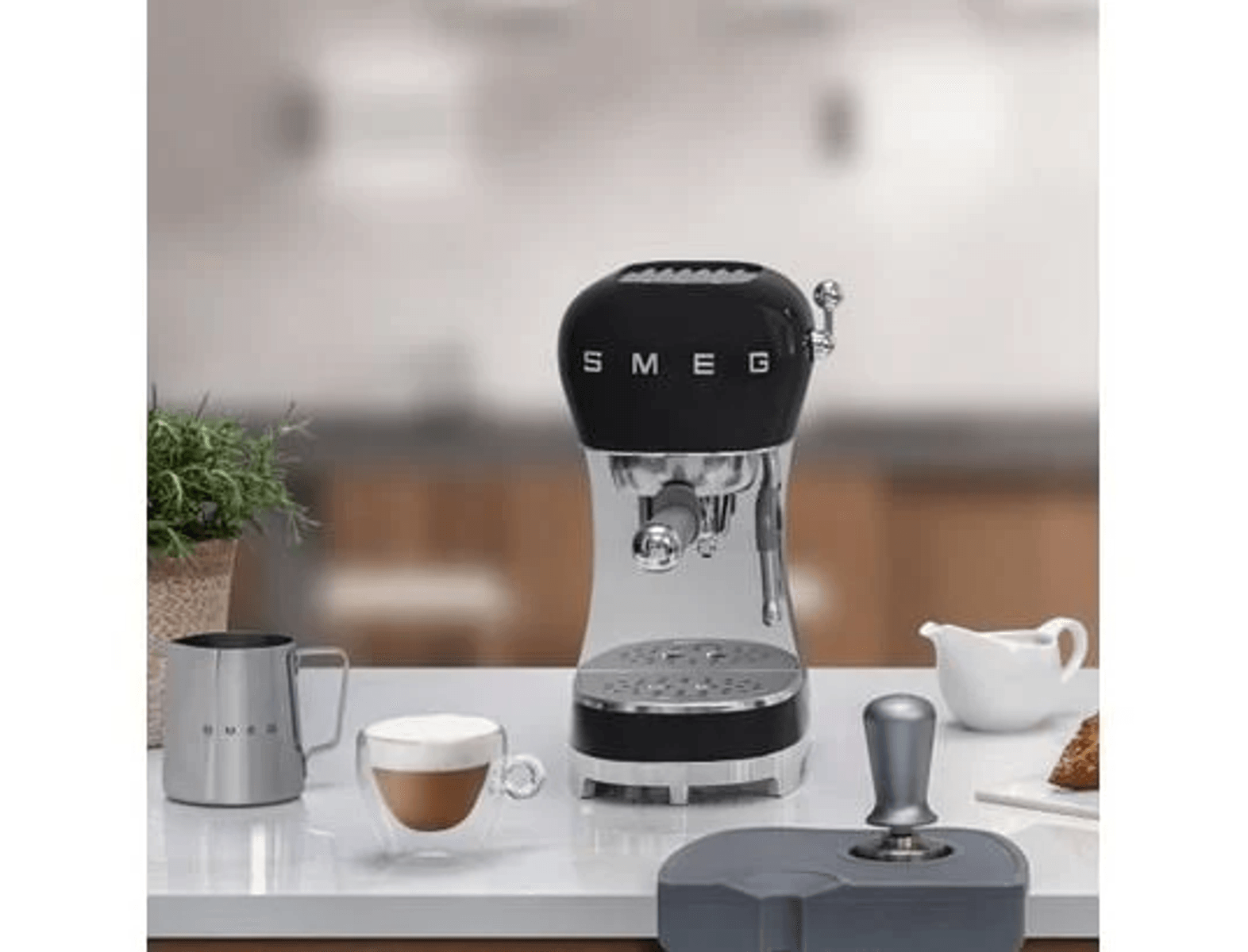 Máquina de espresso SMEG negra con jarra de leche, taza de café y tamper.