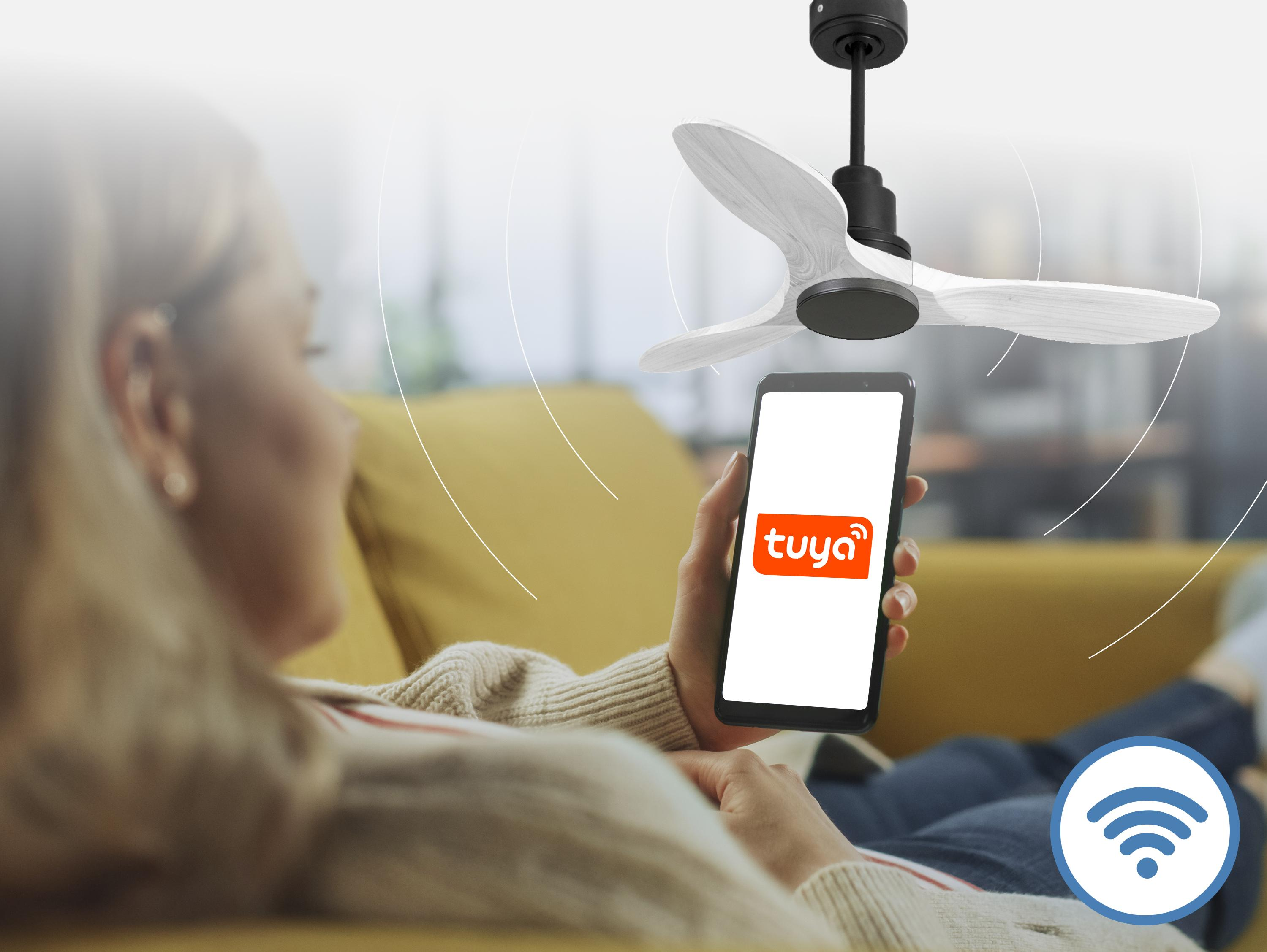 Mujer en sofá controla ventilador de techo con app Tuya en móvil.
