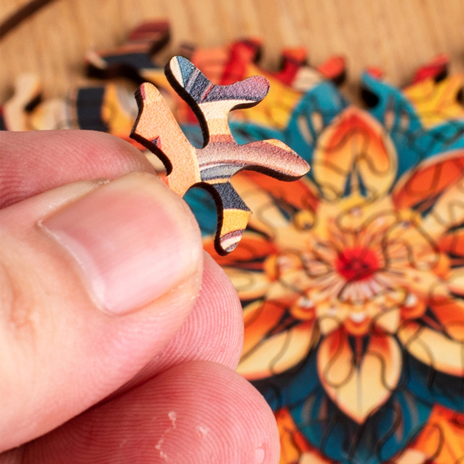 Un dito tiene un pezzo di puzzle colorato con motivi geometrici davanti a un puzzle a mandala.