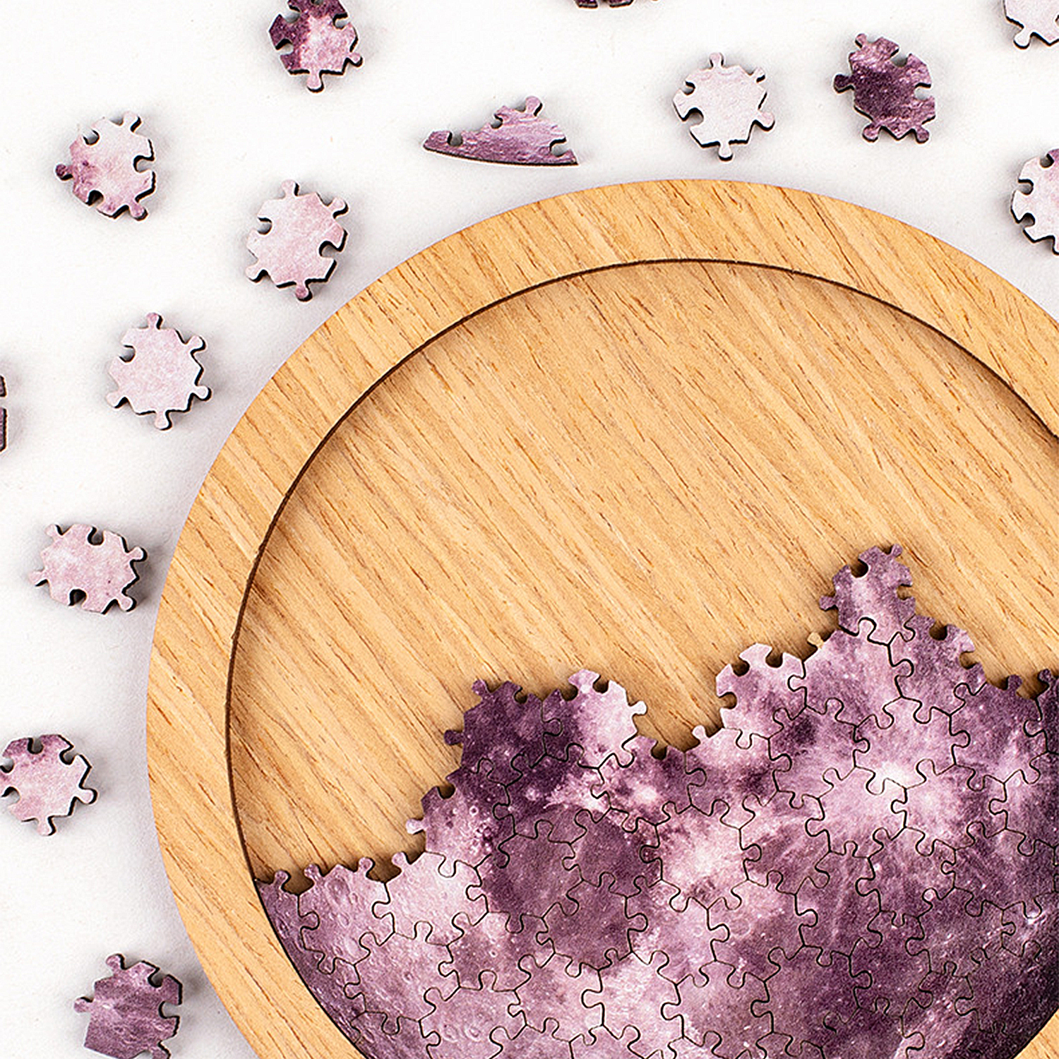 Ciotola di legno con pezzi di puzzle viola della luna e pezzi sparsi.