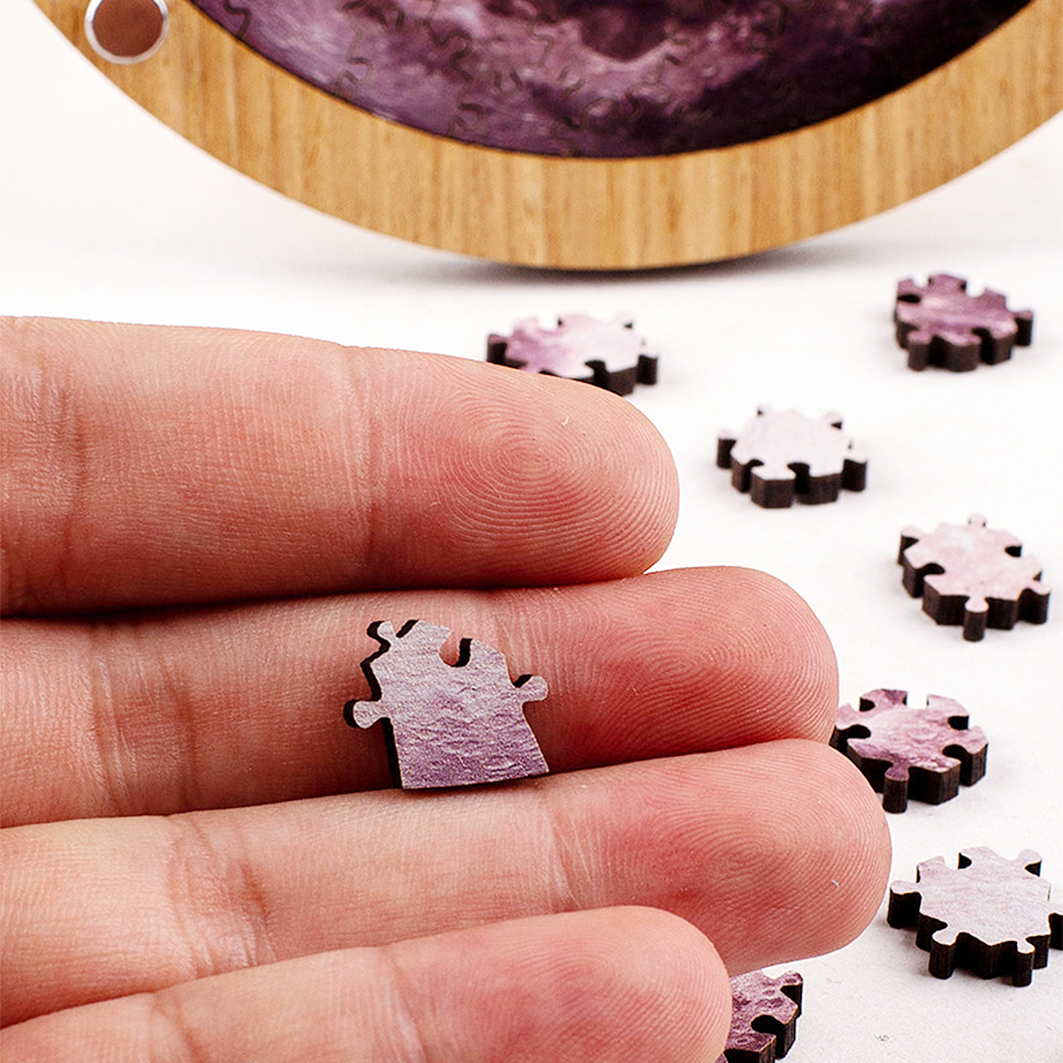 Un dito tiene un piccolo pezzo di puzzle rosa. Altri pezzi sono sparsi intorno.