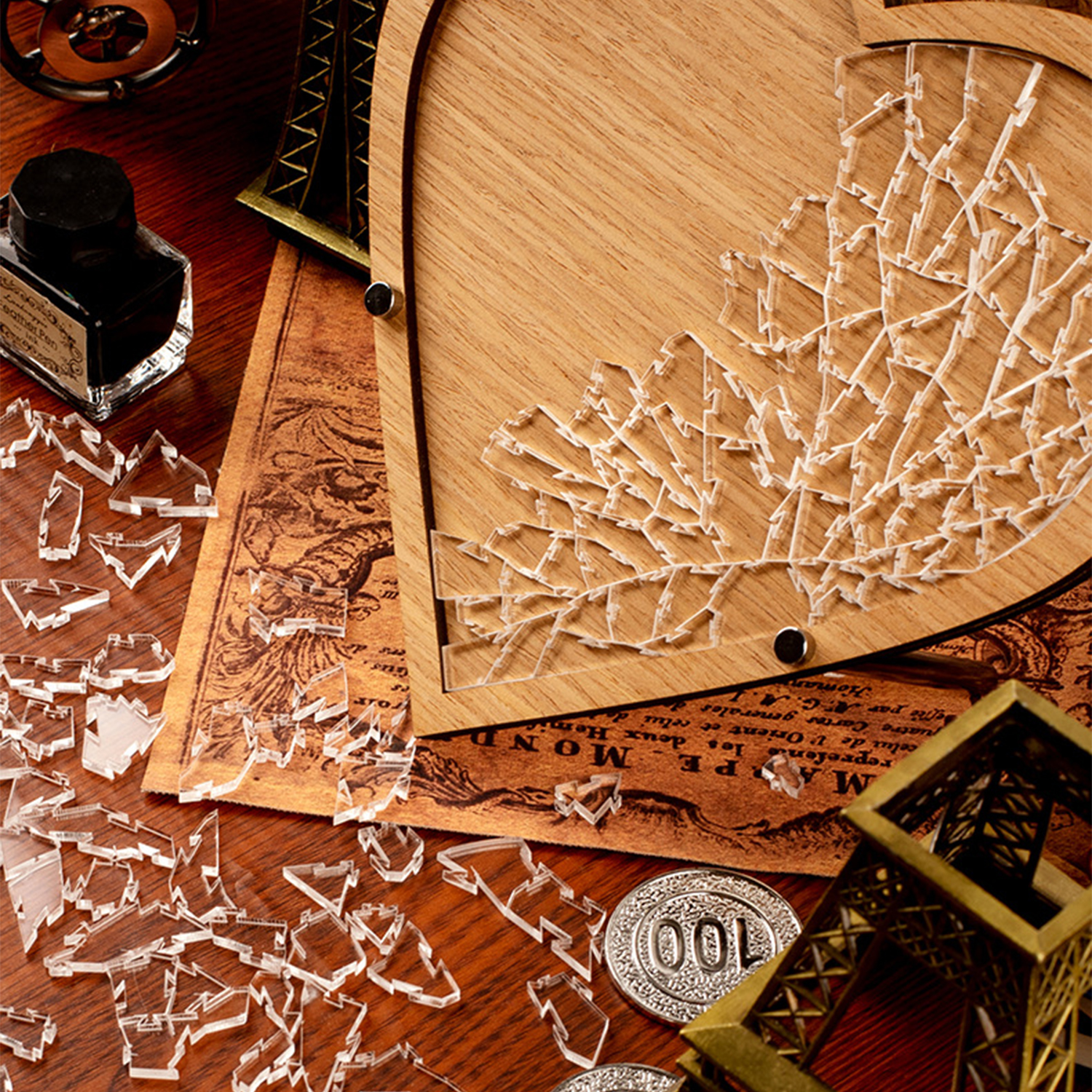 Cornice in legno con pezzi di puzzle trasparenti, bottiglia d'inchiostro e mappa.