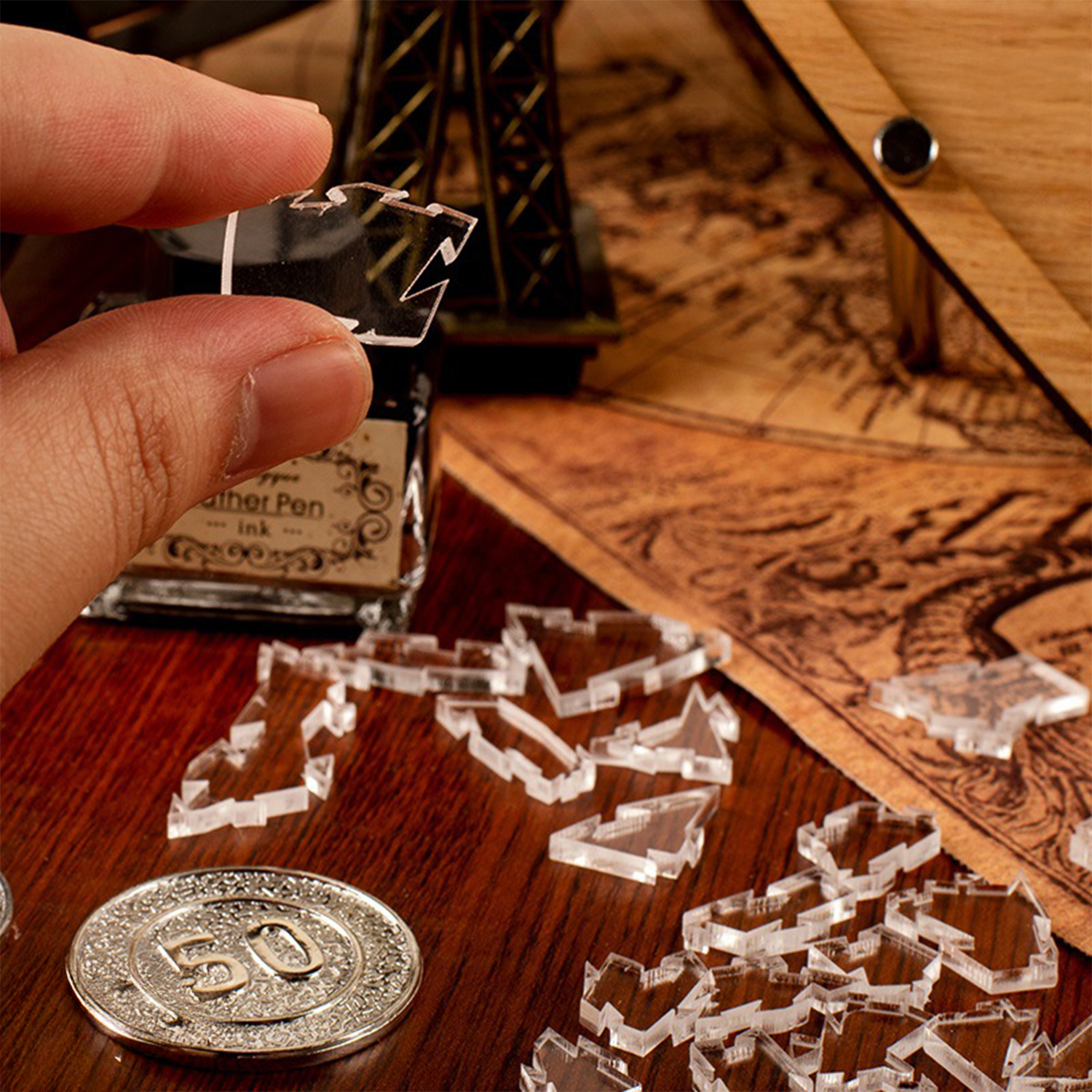 Una mano tiene un pezzo di puzzle trasparente. Una moneta e molti pezzi sul tavolo.