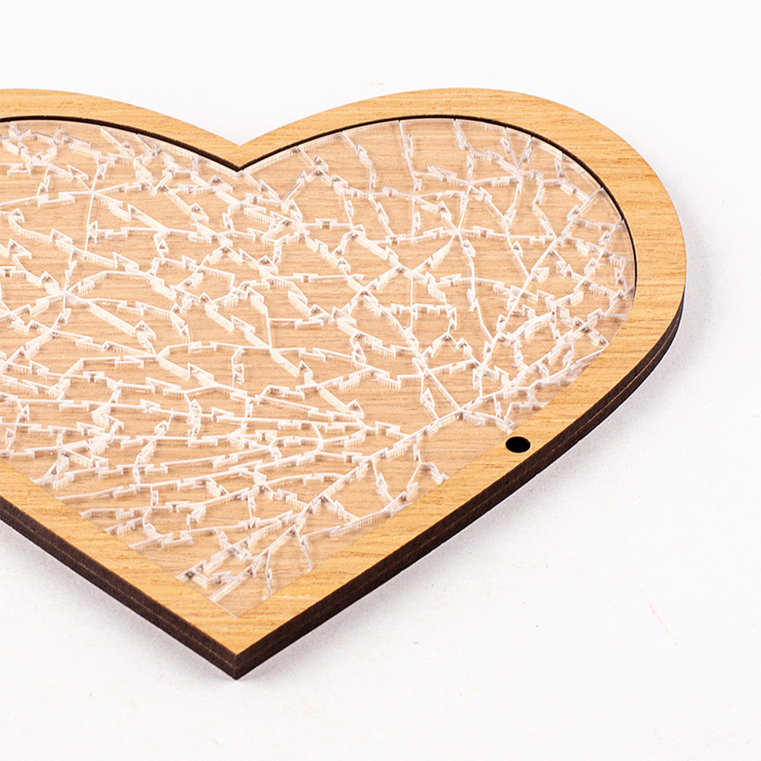 Un oggetto a forma di cuore in legno con un intarsio in plastica trasparente a motivi geometrici.