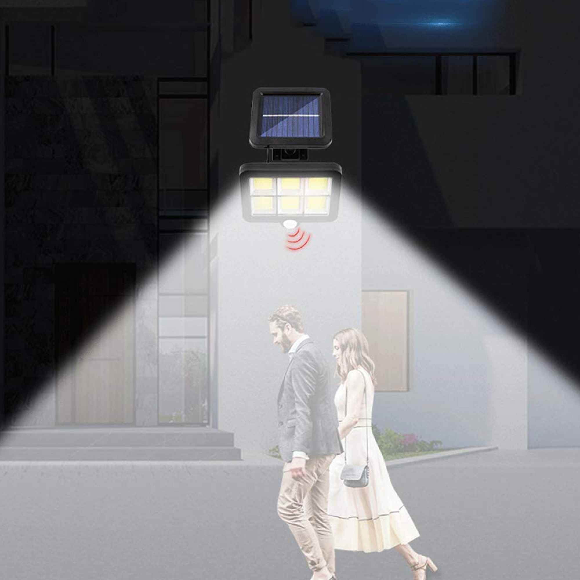 Ein Paar geht nachts an einem solarbetriebenen Licht vorbei, das eine Wand beleuchtet.