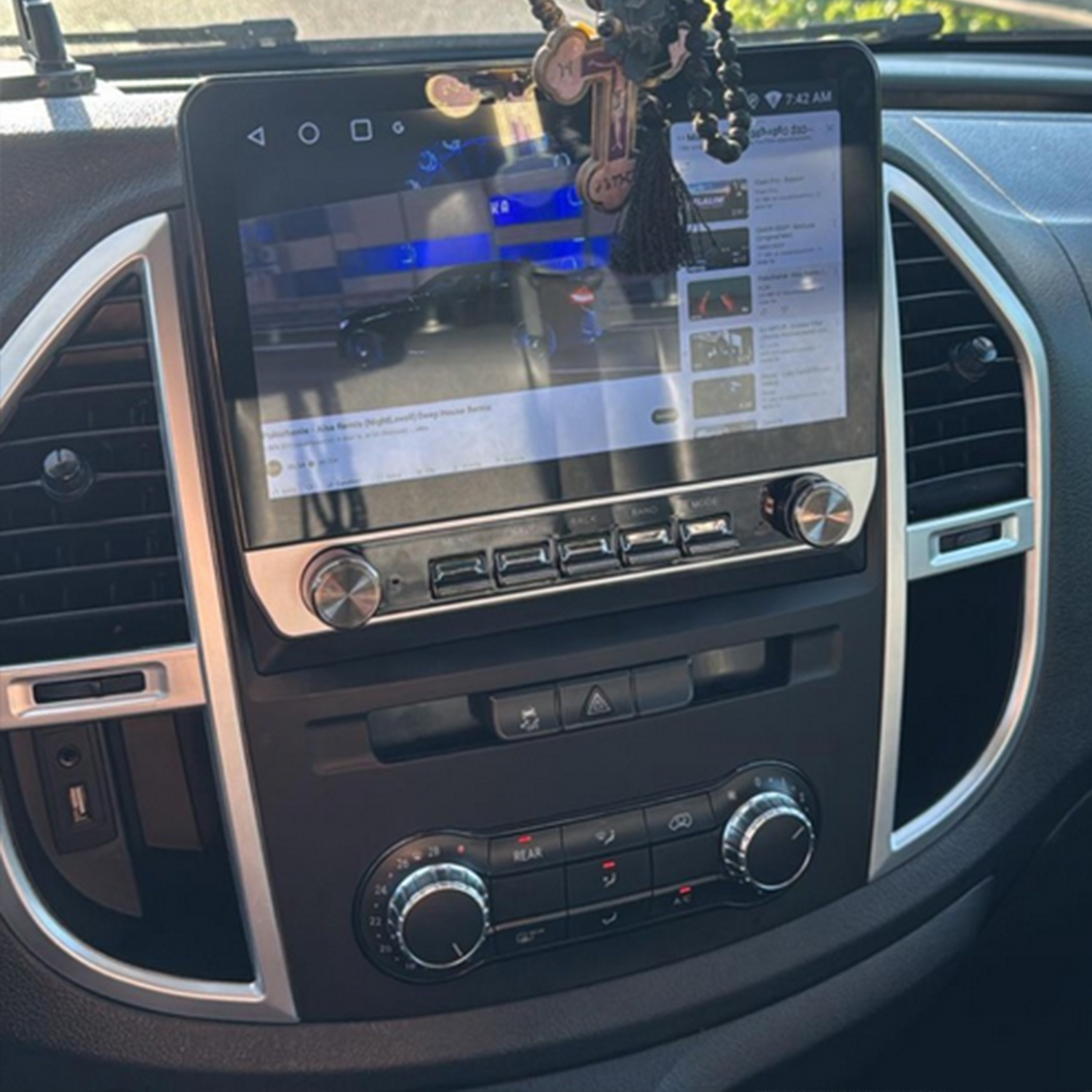 Armaturenbrett mit Touchscreen, der ein Auto-Video zeigt, und Klimaregelung.