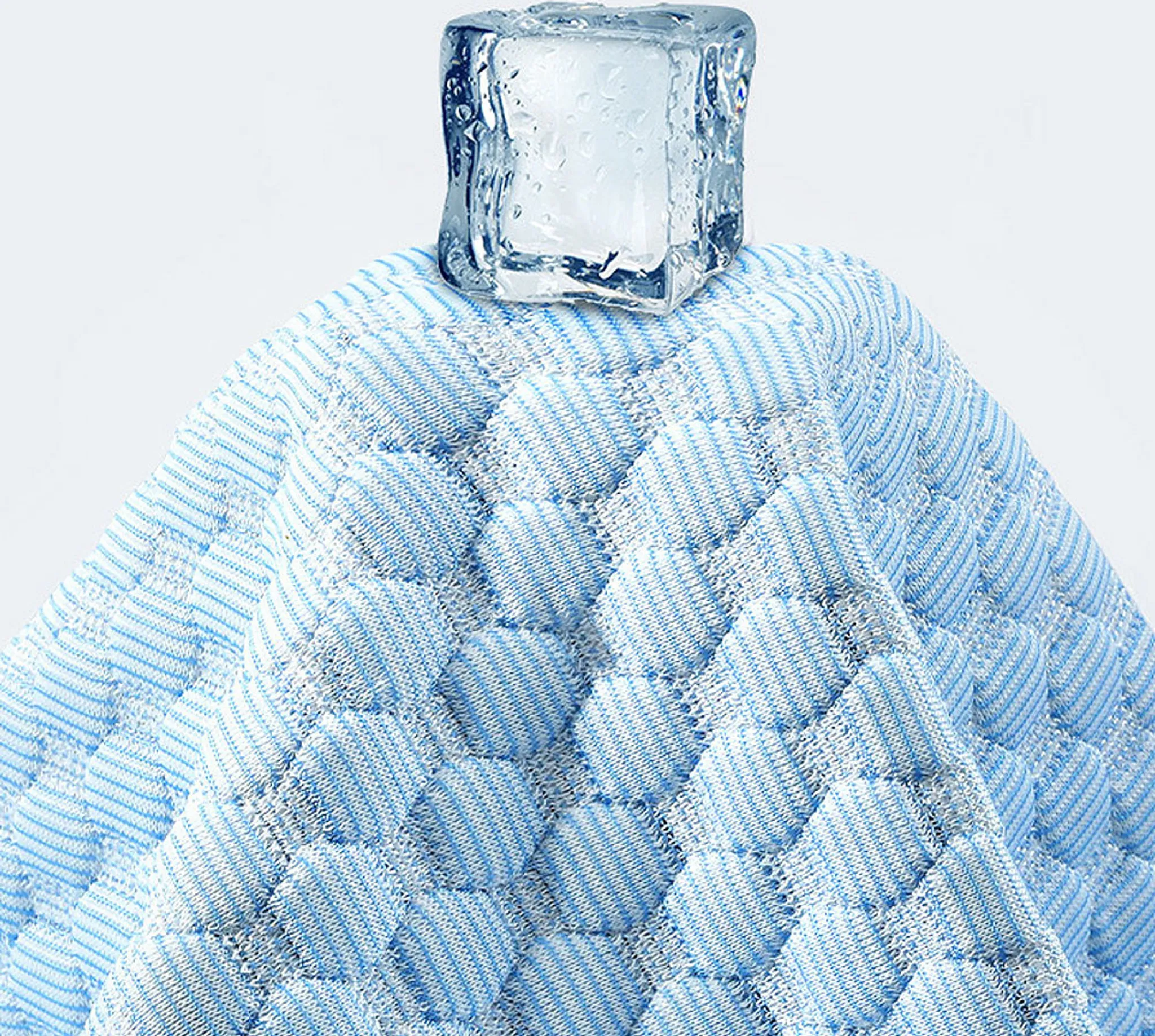 Ein Eiswürfel liegt auf blau-weiß gestreiftem Stoff mit Wabenmuster.
