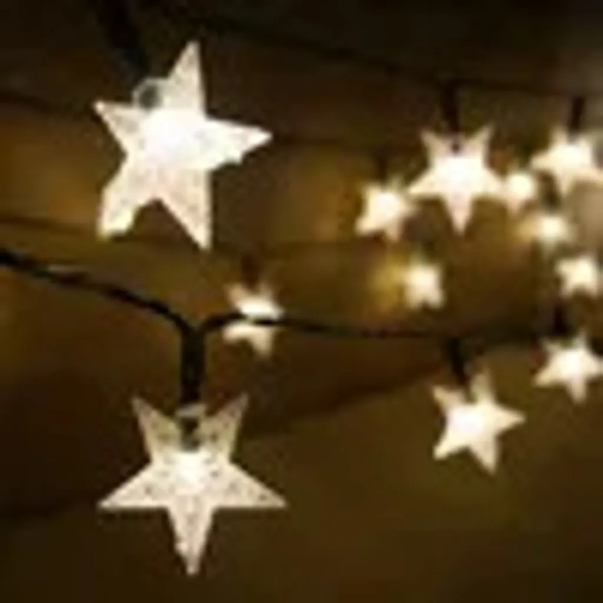 Lichterkette mit weißen Sternen auf dunklem Hintergrund.