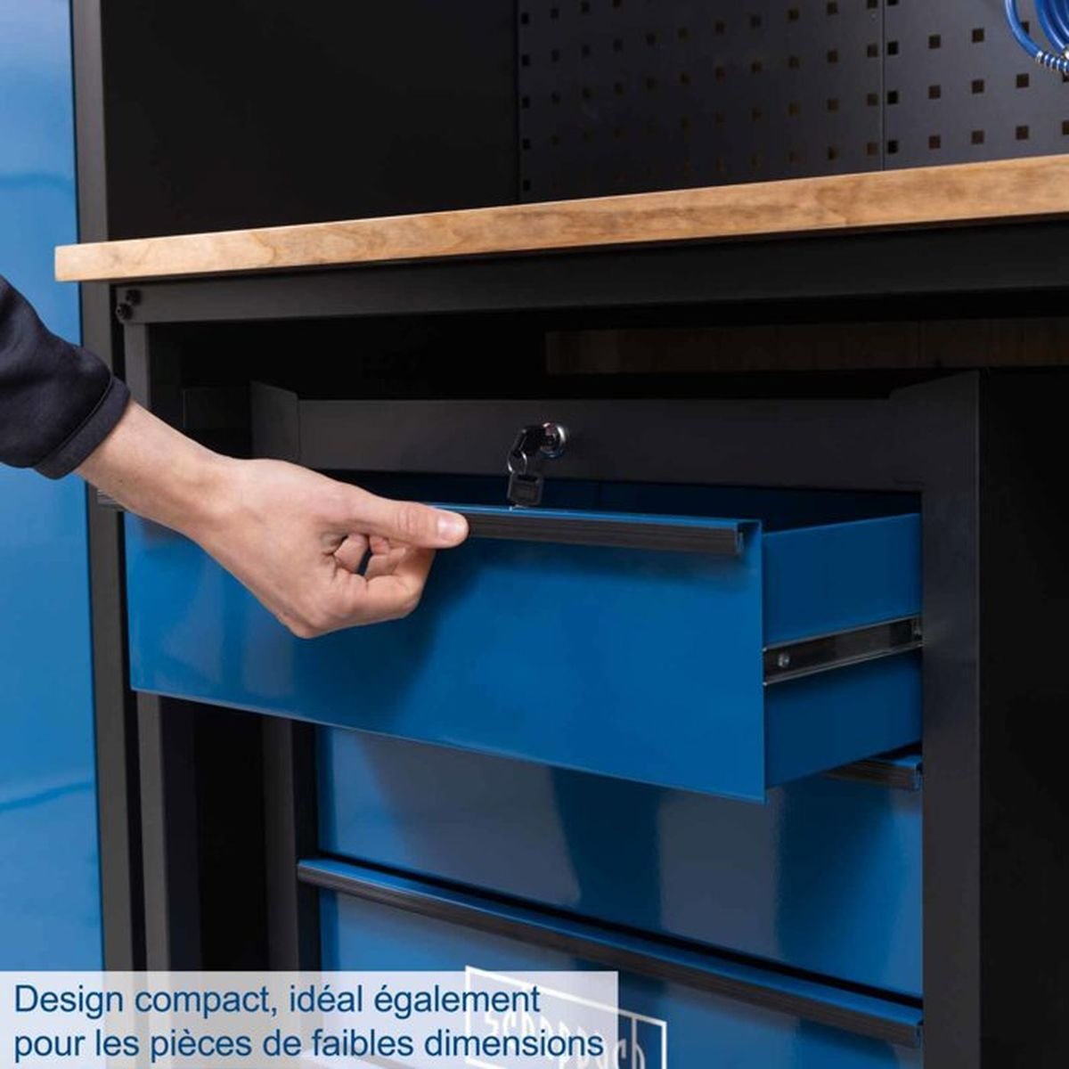 Eine Hand öffnet eine blaue Schublade eines Werkzeugschranks mit Holzplatte.