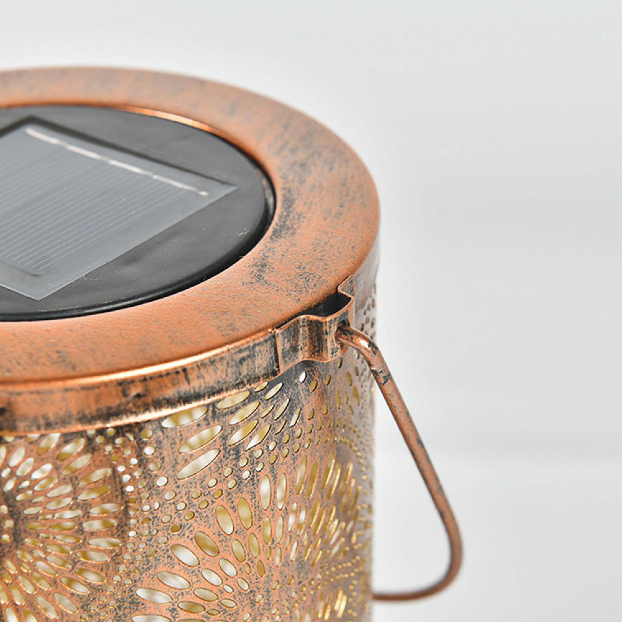 Eine bronzefarbene Solarlaterne mit offenem Gittermuster und einem Henkel.