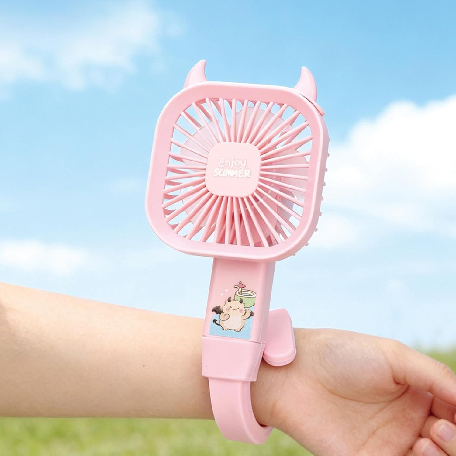 Ein rosa Handventilator mit Teufelshörnern, der am Handgelenk getragen wird.