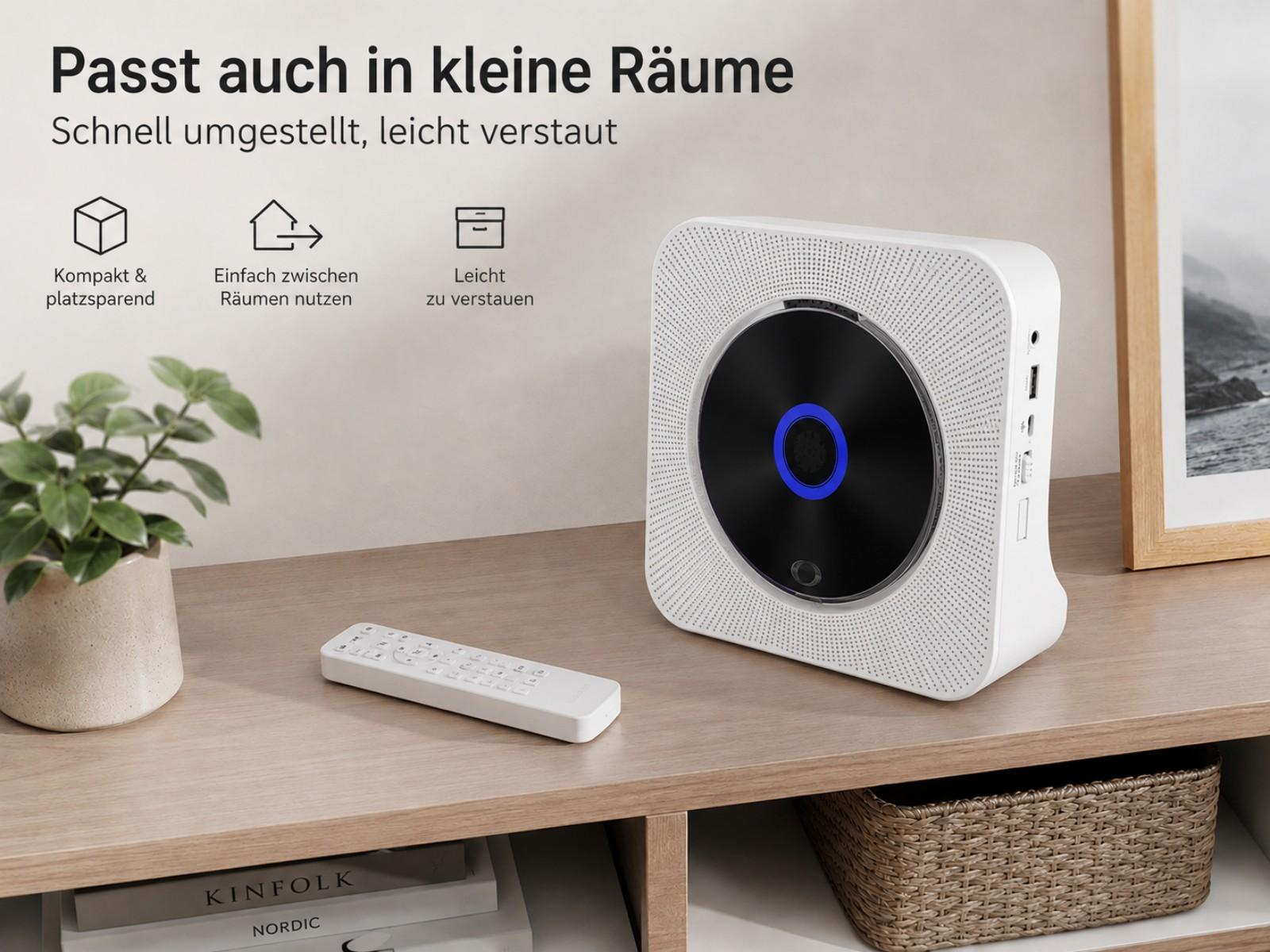 Ein weißer CD-Player mit Fernbedienung, Pflanze und Korb auf einem Regal.