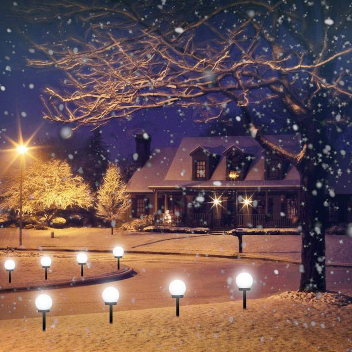 Schneebedecktes Haus mit leuchtenden Kugelleuchten auf der Auffahrt bei Nacht.