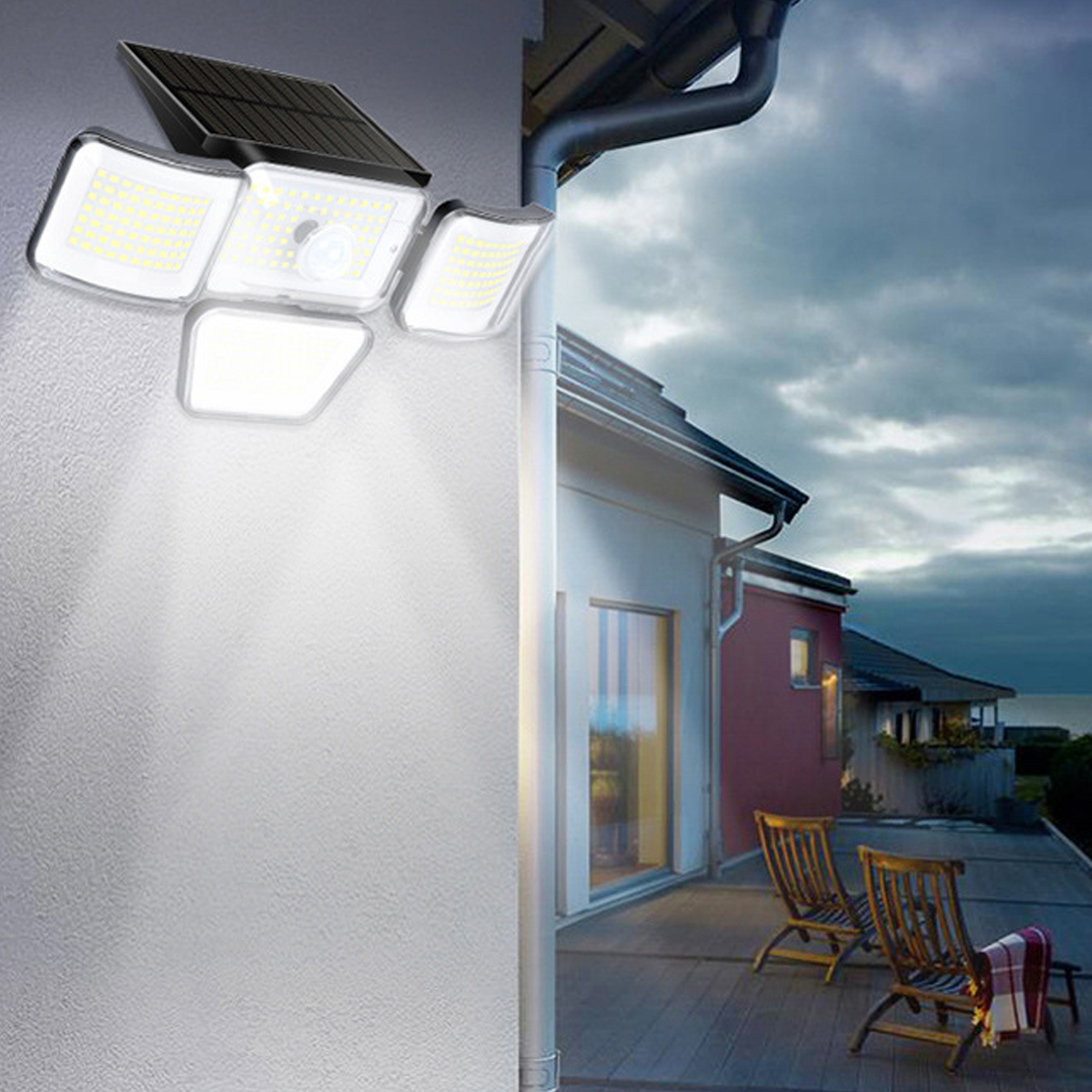 Solar-Außenleuchte beleuchtet eine weiße Wand, daneben ein Haus mit zwei Stühlen auf der Terrasse.