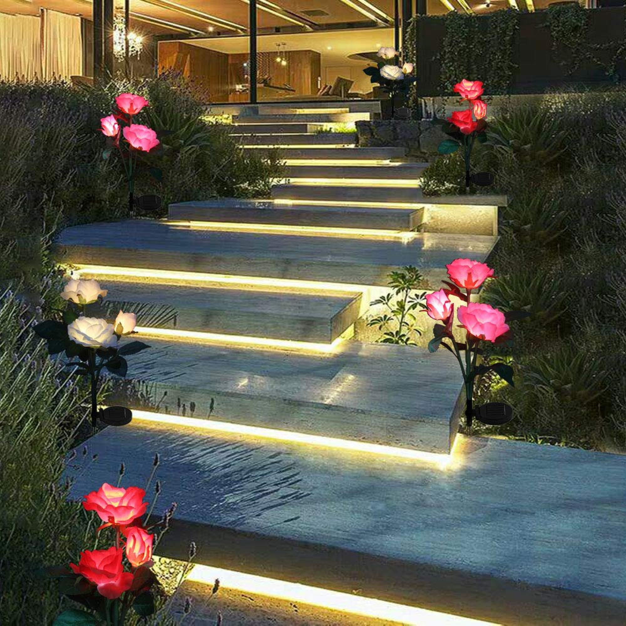 Beleuchtete Rosenlampen säumen eine Steintreppe, die zu einem Haus führt.