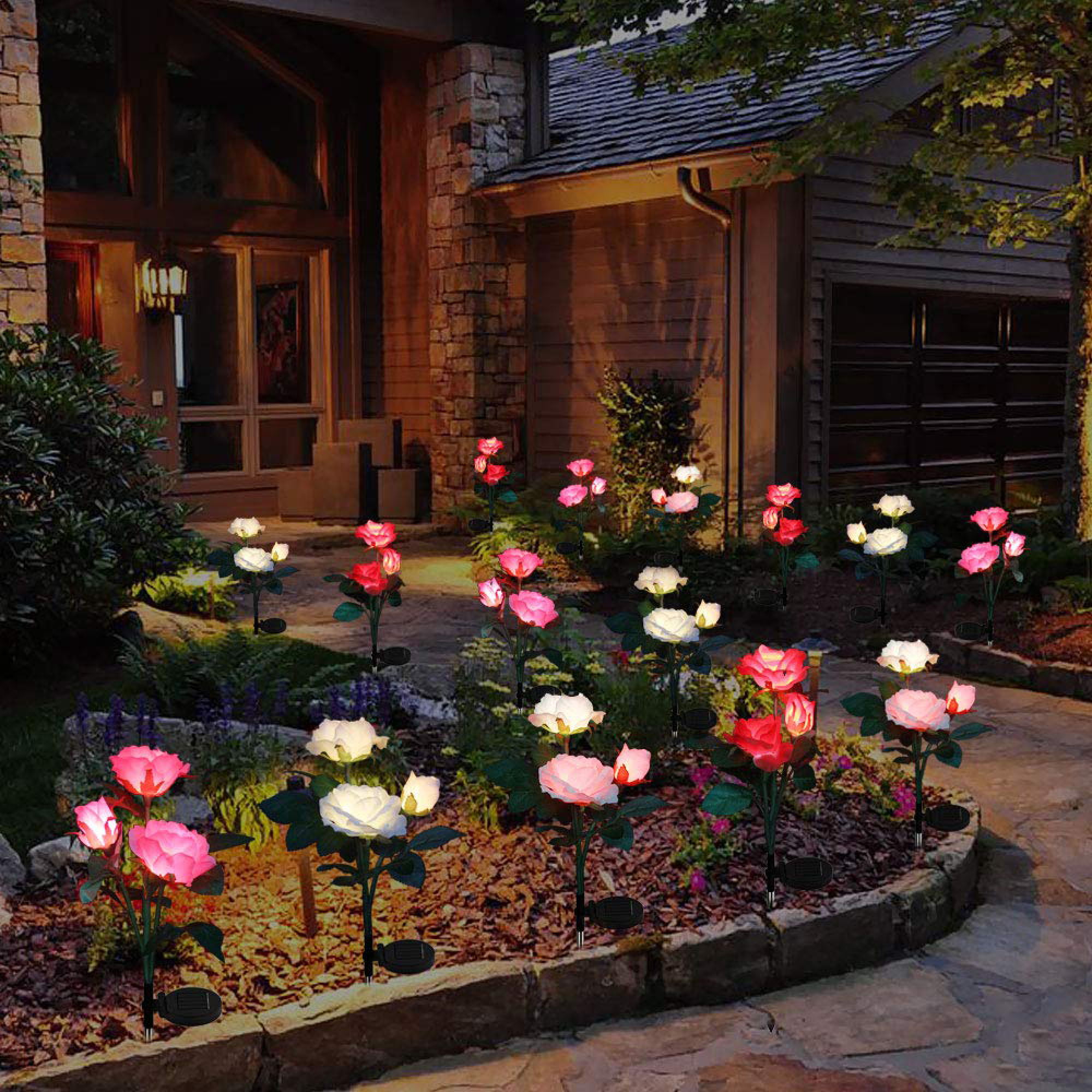 Beleuchtete Rosenlichter schmücken einen Vorgarten vor einem Haus bei Nacht.