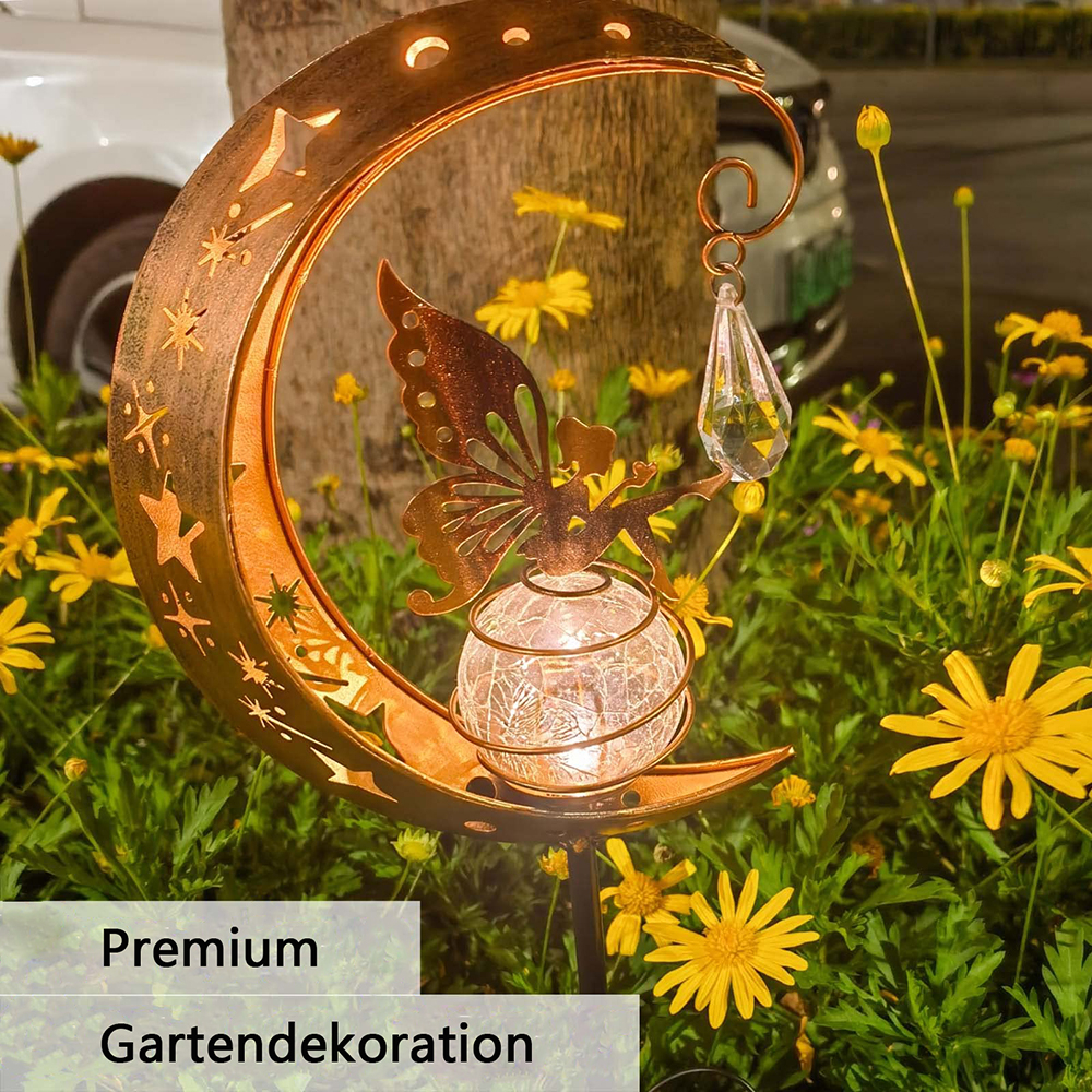 Gartenlampe mit Fee, Mond und Glaskugel im Abendlicht zwischen gelben Blumen.
