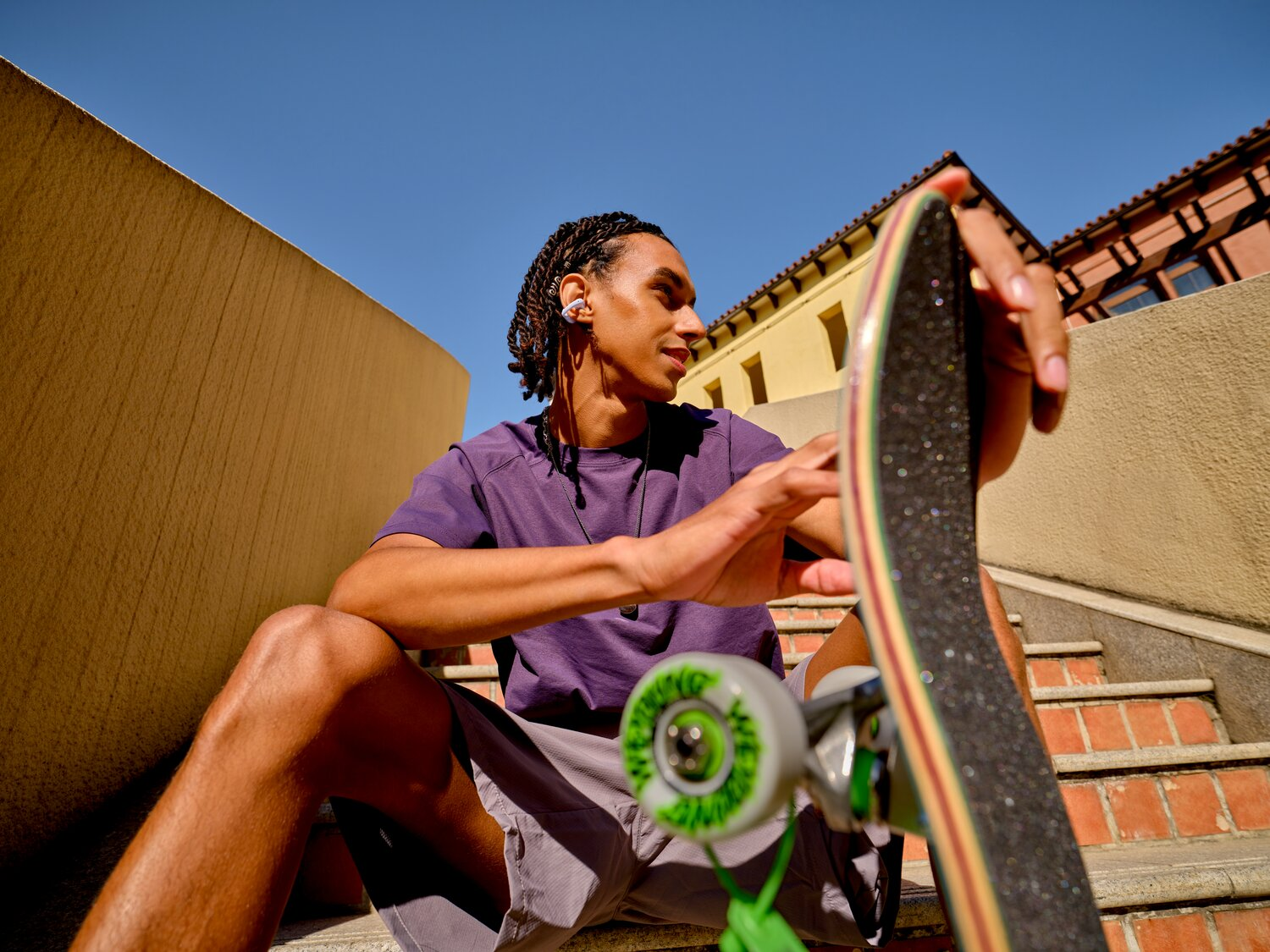 Un uomo con i capelli intrecciati è seduto sulle scale con uno skateboard.