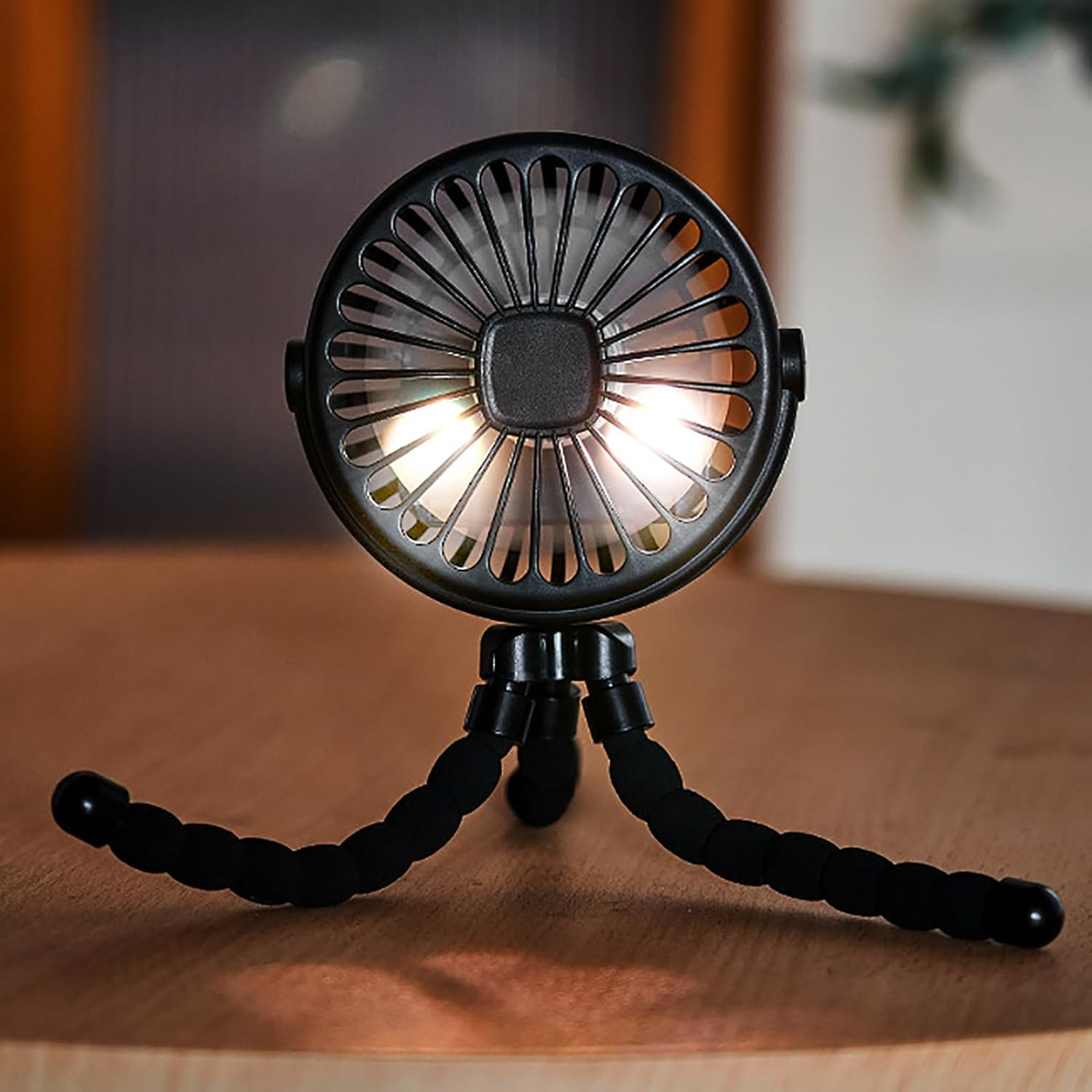 Ein schwarzer Mini-Ventilator mit flexiblem Stativ auf einem Holztisch.