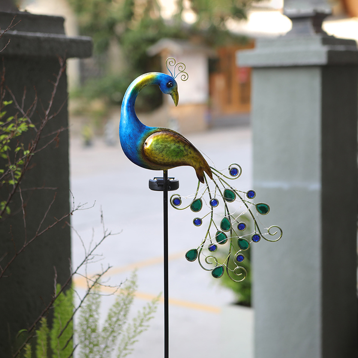 Ein Metallpfau-Gartenstecker mit blauen und grünen Federn und geschwänztem Schwanz.