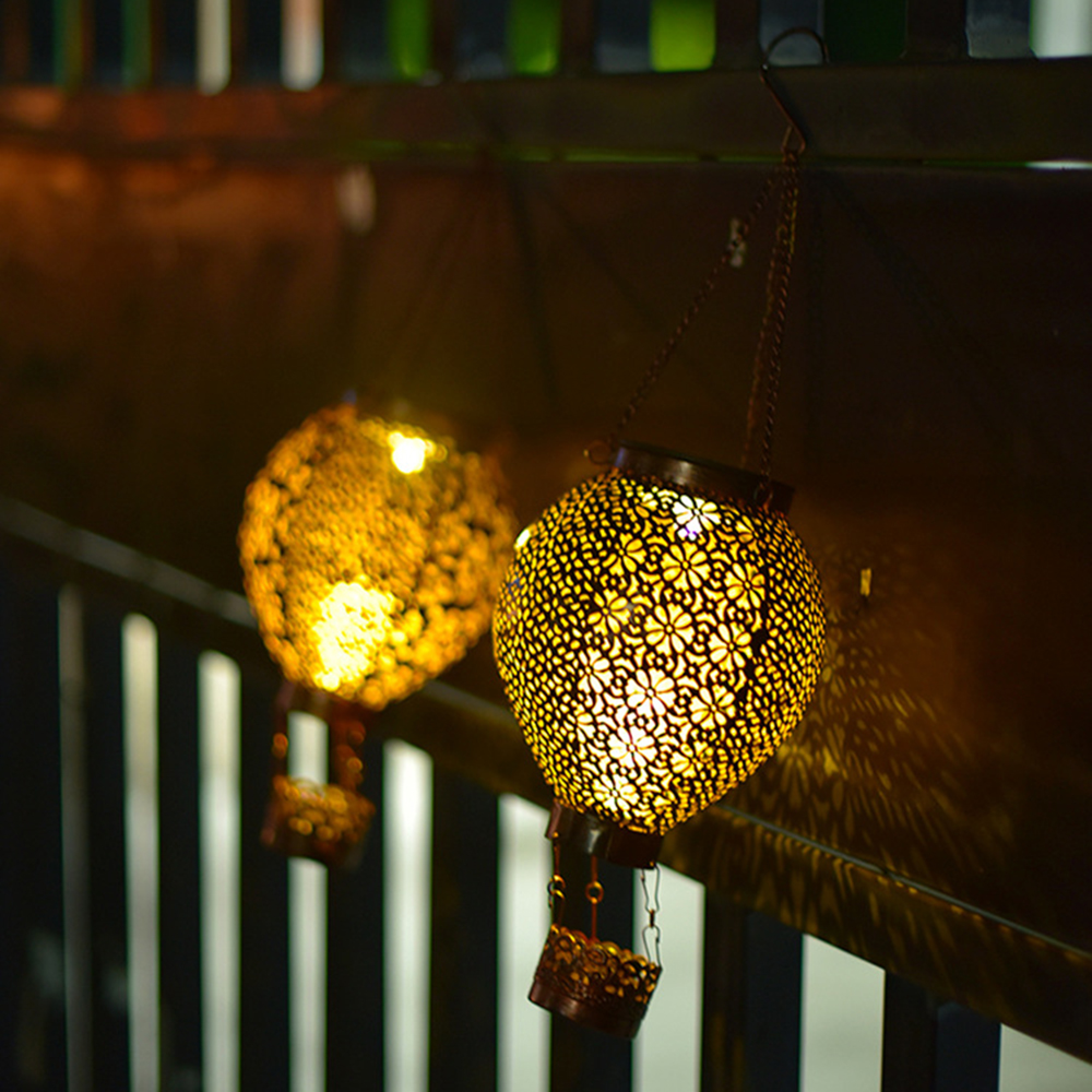 Zwei verzierte, goldene Laternen in Form von Heißluftballons hängen nachts.