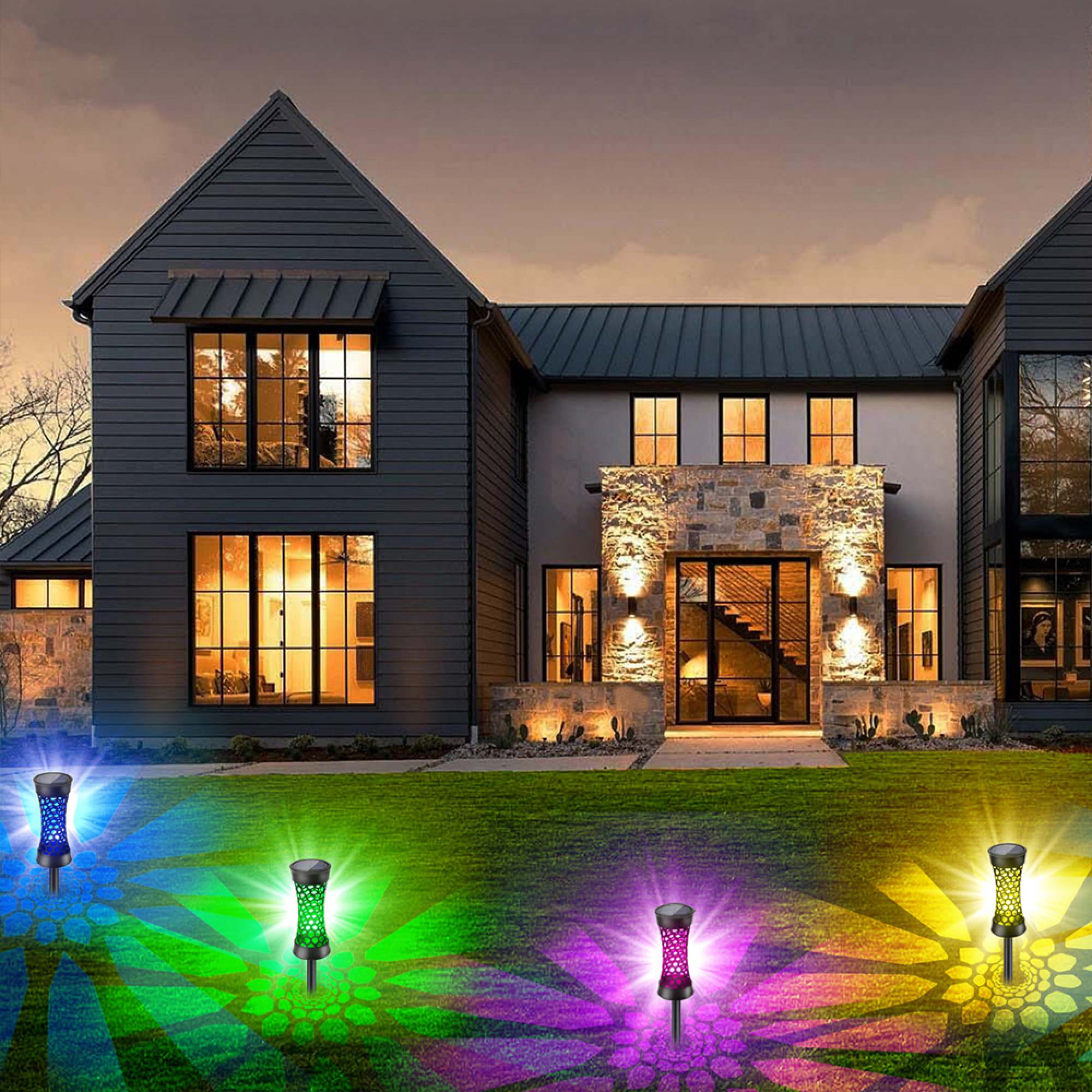 Mehrere bunte Solarleuchten beleuchten einen Rasen vor einem modernen Haus bei Dämmerung.
