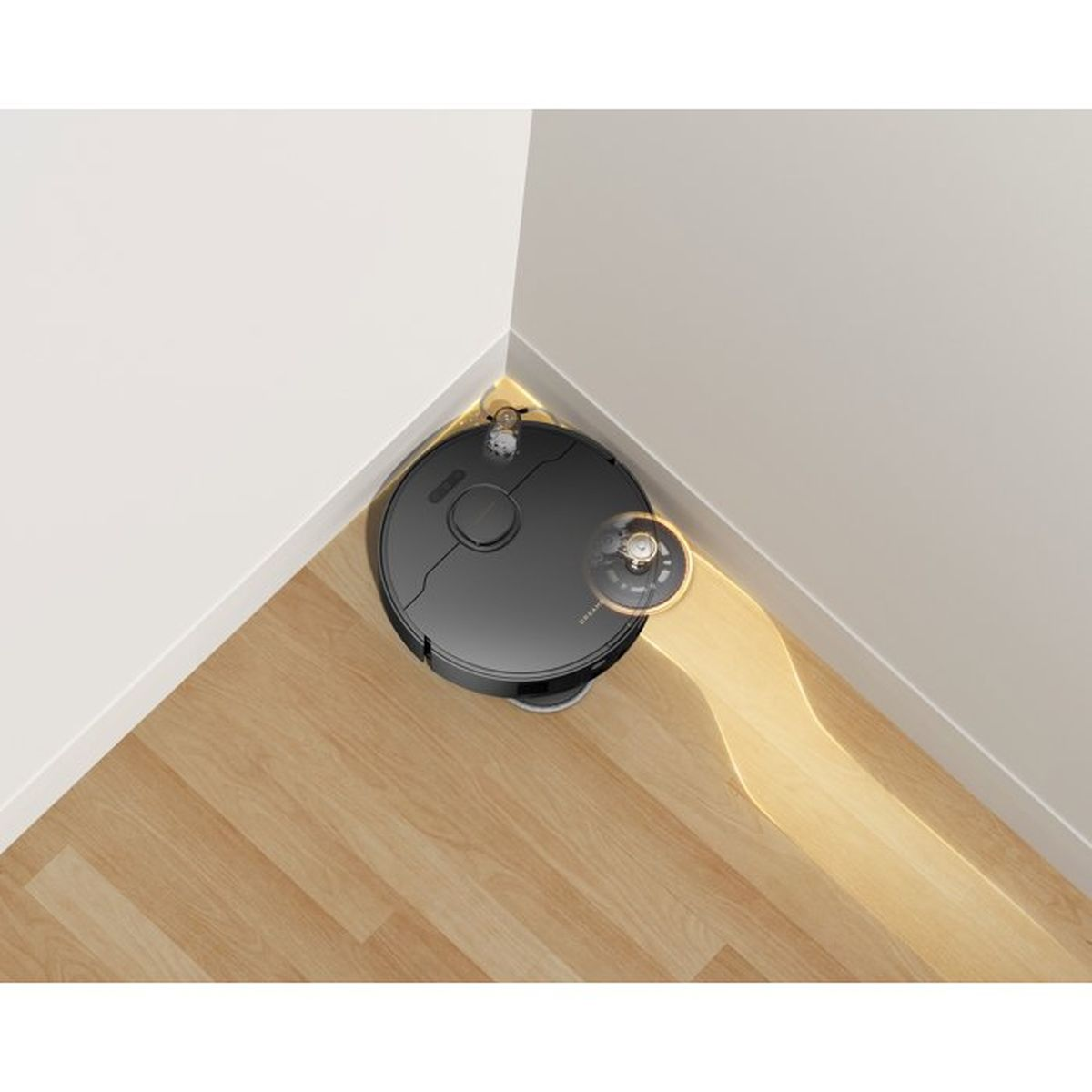 Un robot aspirapolvere nero pulisce un angolo di un pavimento in legno.