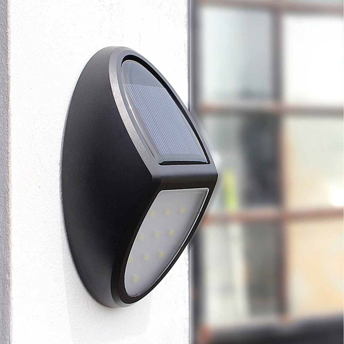 Schwarze Solar-Wandleuchte mit LED und Sonnenkollektor an weißer Wand.