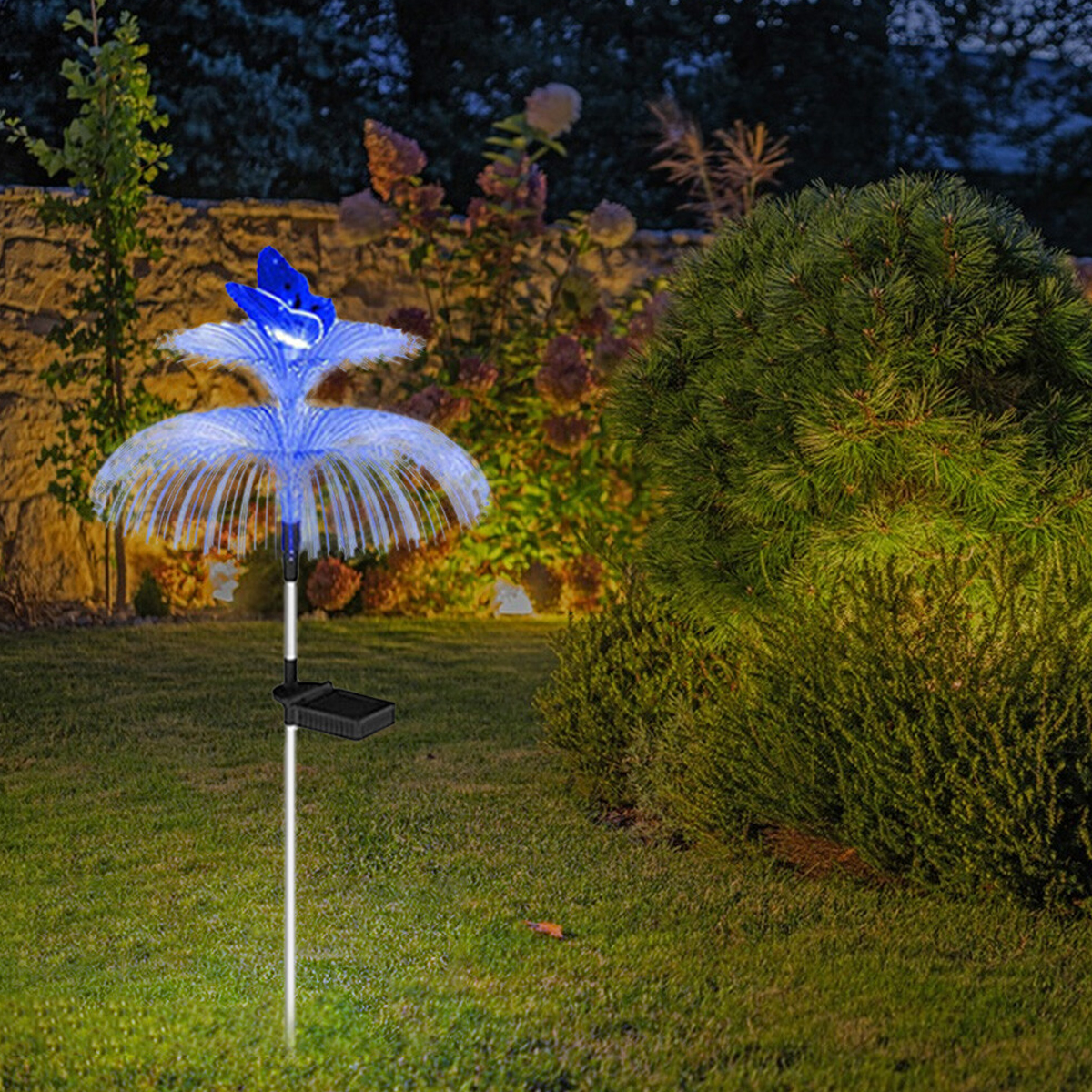 Eine blaue Schmetterlingslaterne leuchtet auf einem Rasen im Garten.