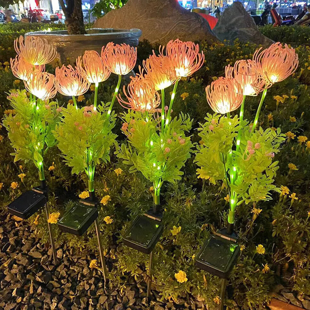 Leuchtende Blumenlampen mit Solarbetrieb im Garten bei Nacht.