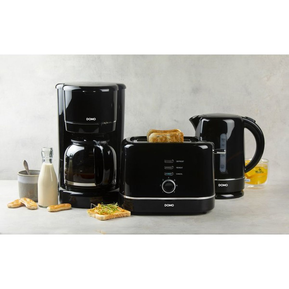 Schwarze Kaffeemaschine, Toaster mit Toast und Wasserkocher auf einer Arbeitsplatte.