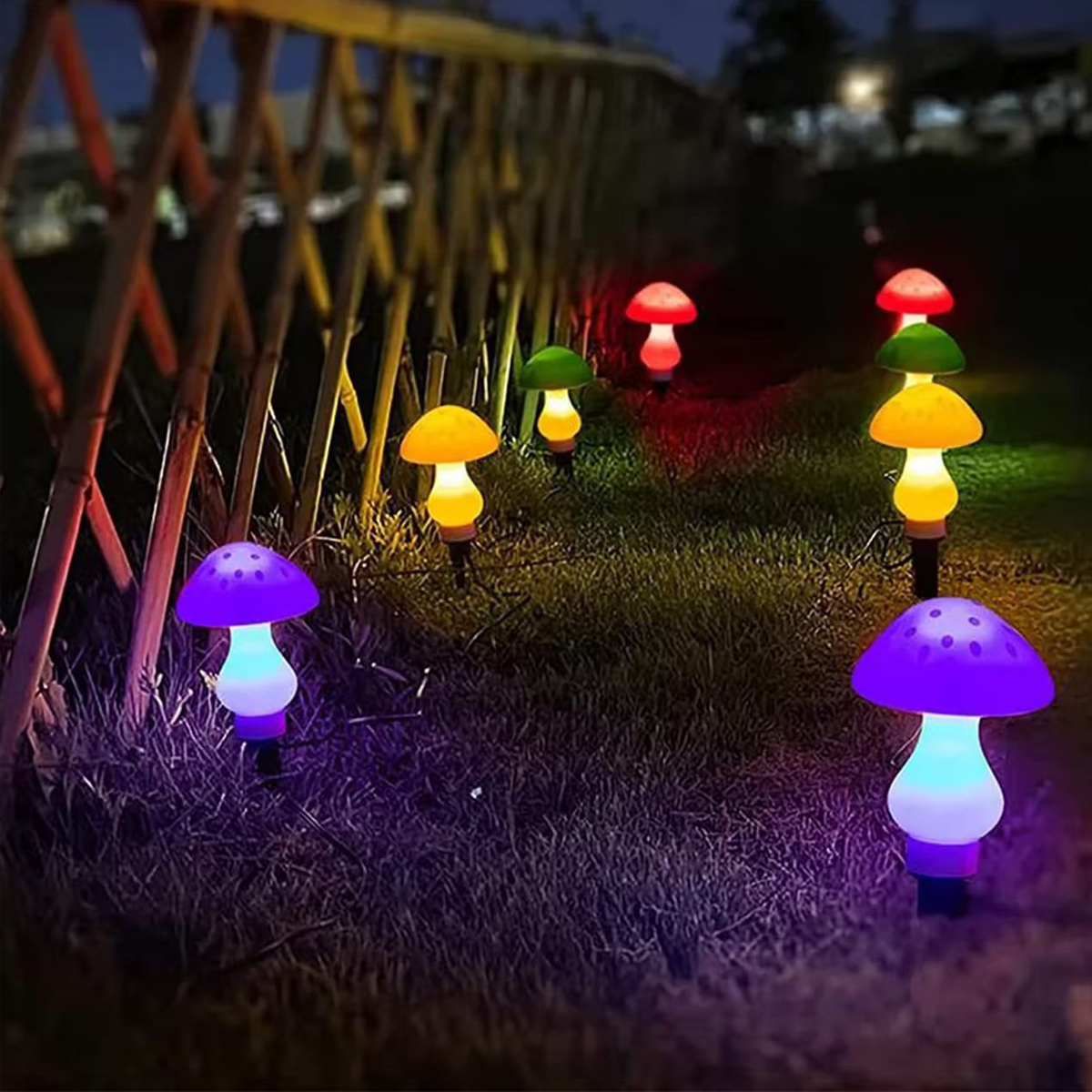 Pilzförmige Gartenleuchten in Lila, Gelb, Grün und Rot leuchten in der Dämmerung.
